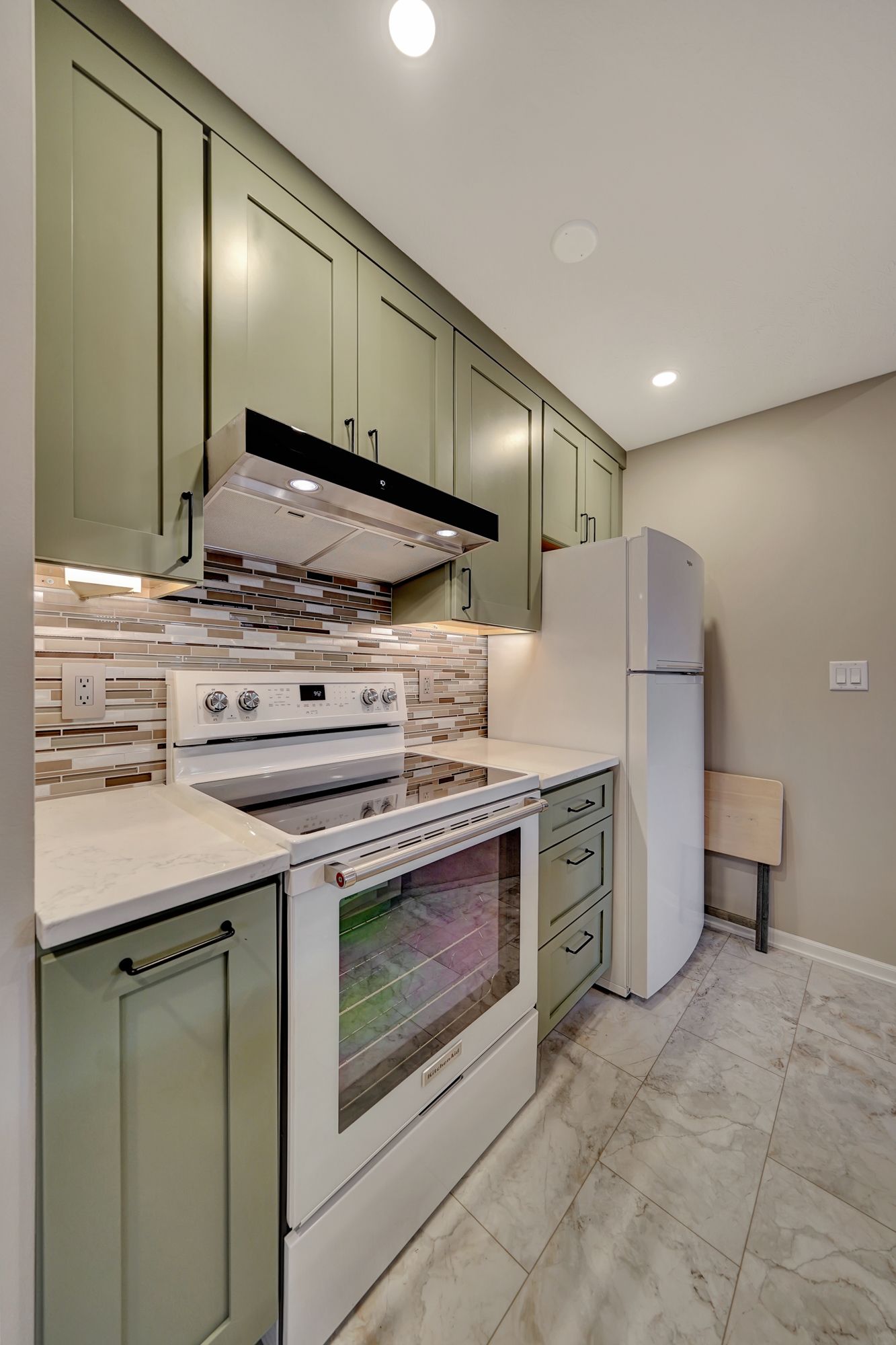A kitchen with green cabinets , white appliances , and a refrigerator | Lincoln, NE | SkyLimit Remodeling