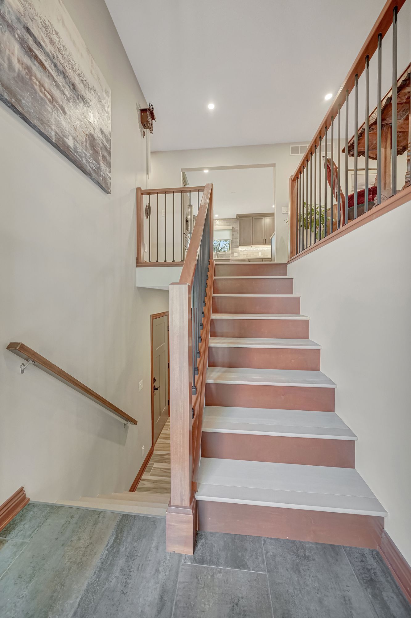 Staircase with wooden handrails and steps, leading up to a doorway and down to a door.