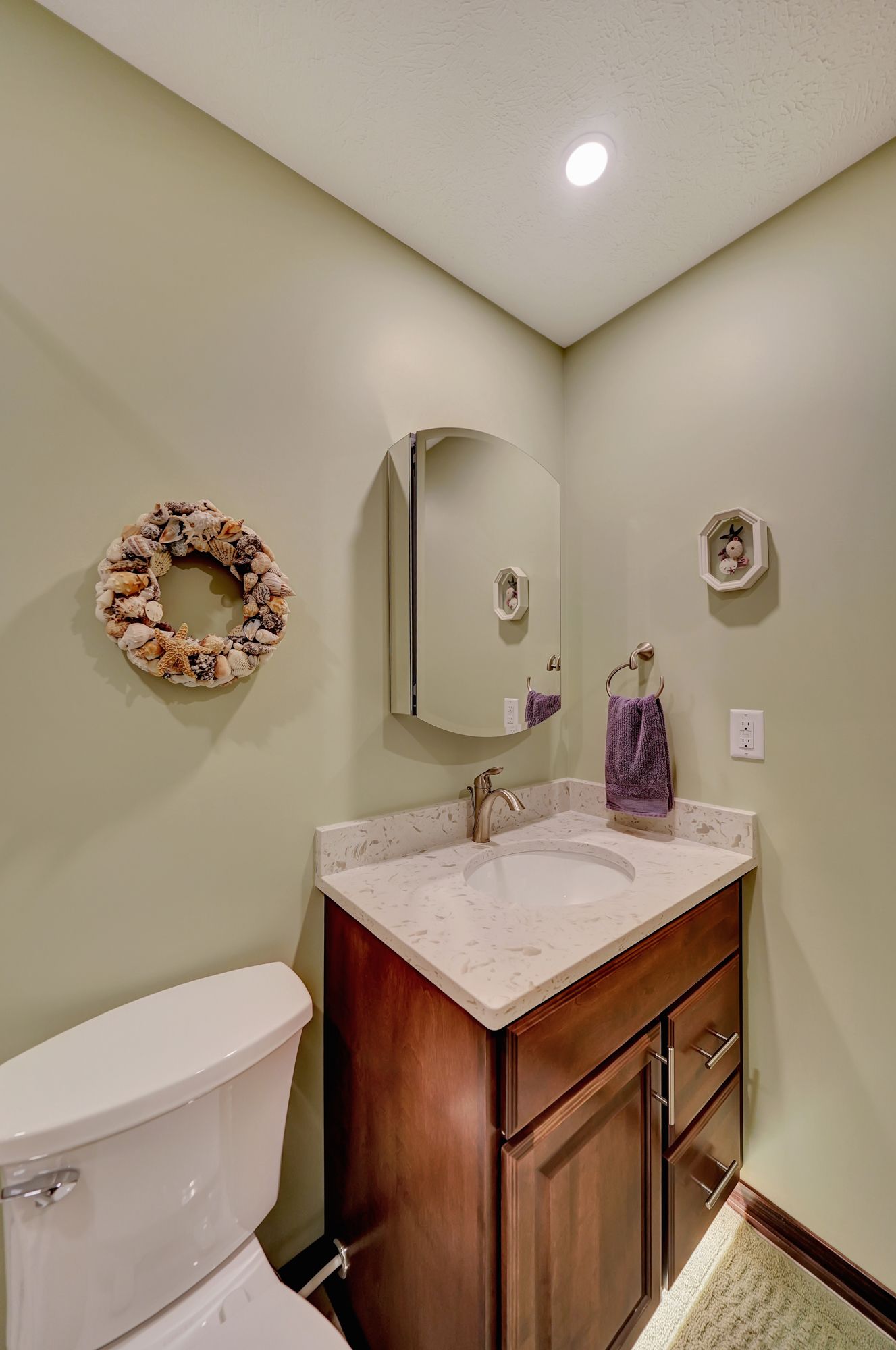 A Bathroom with a Toilet, Sink, Mirror and Wreath on the Wall | Lincoln, NE | SkyLimit Remodeling