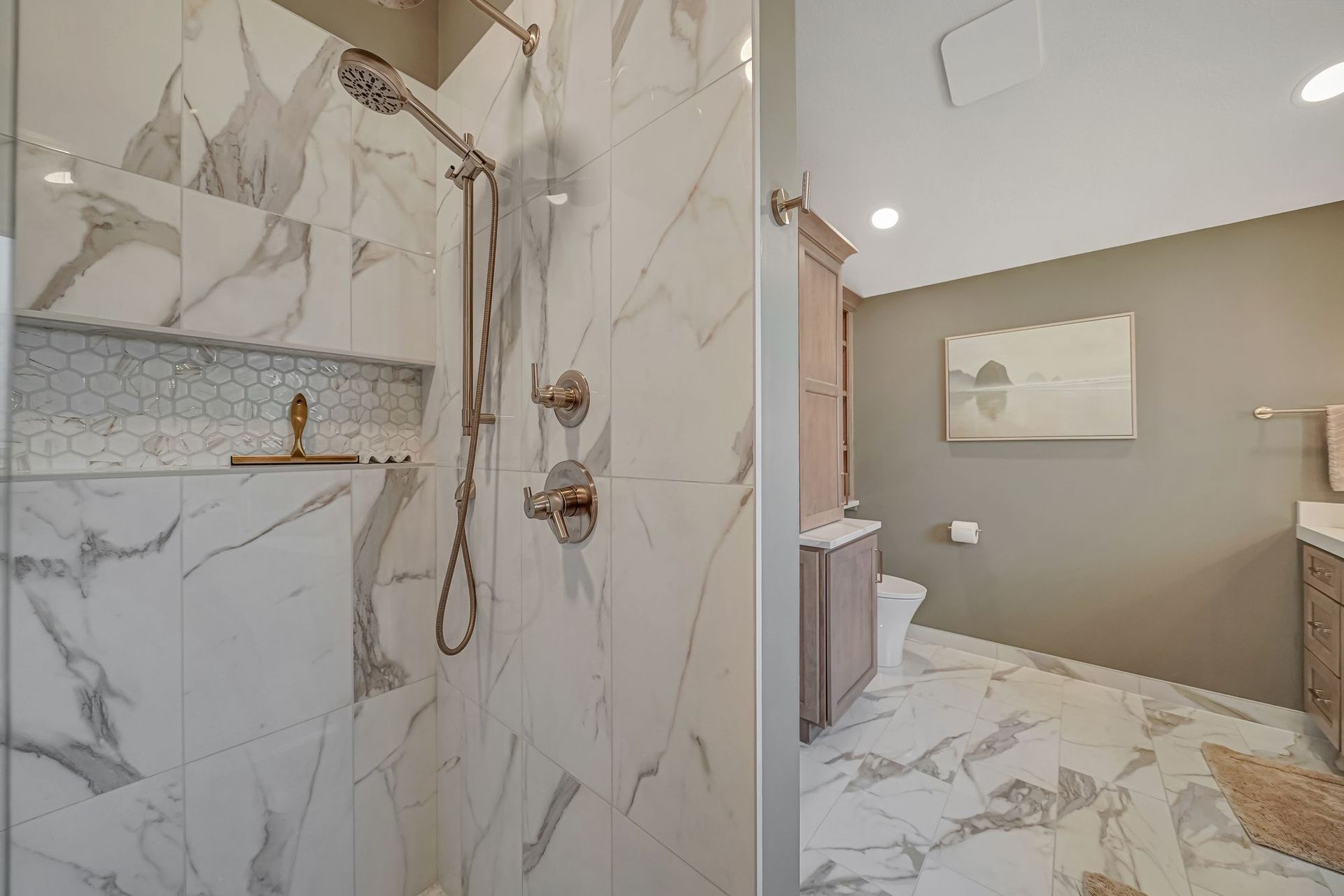 Luxurious marble tiled shower and bathroom with muted wall, toilet, and vanity.