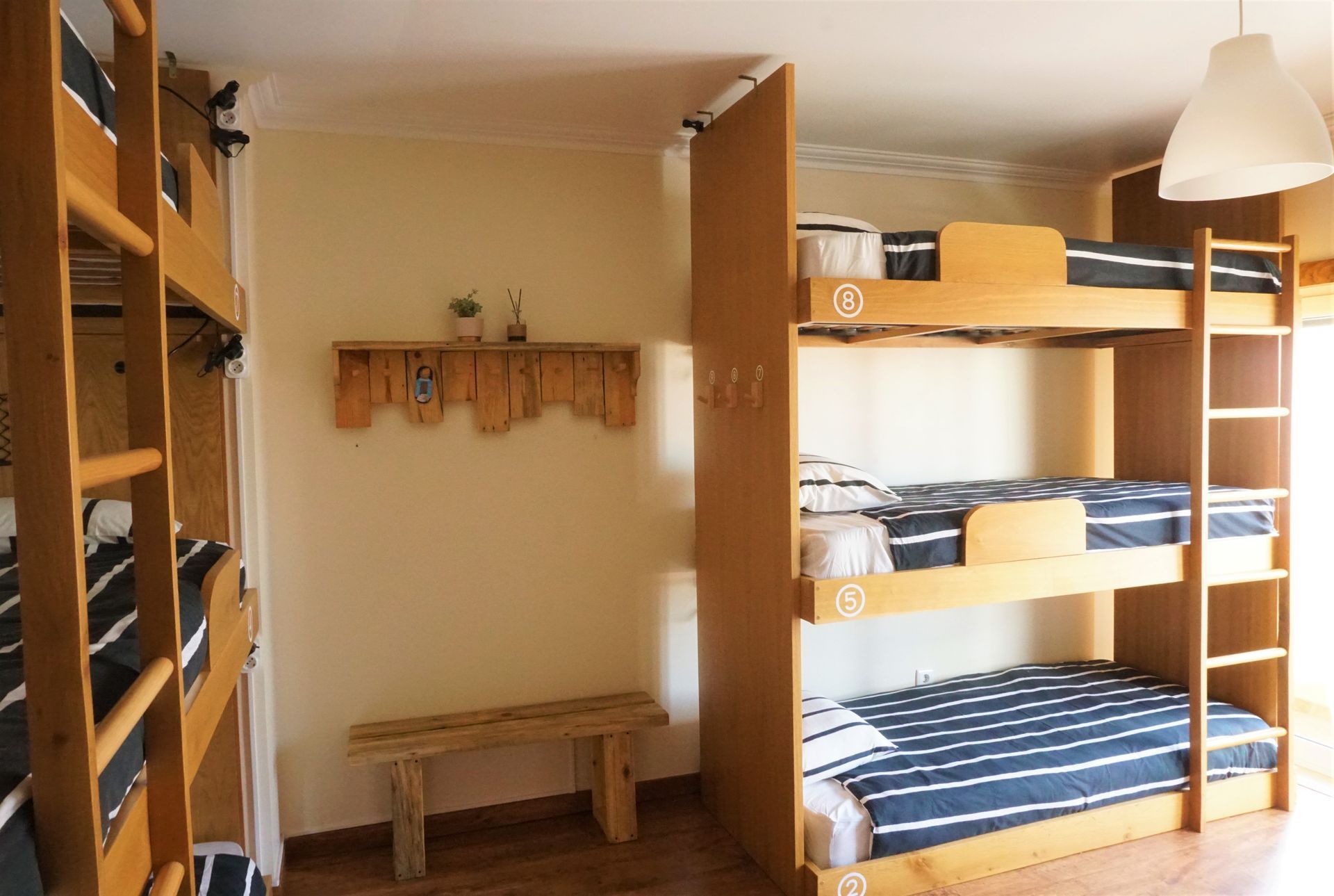 A room with three bunk beds and a bench.