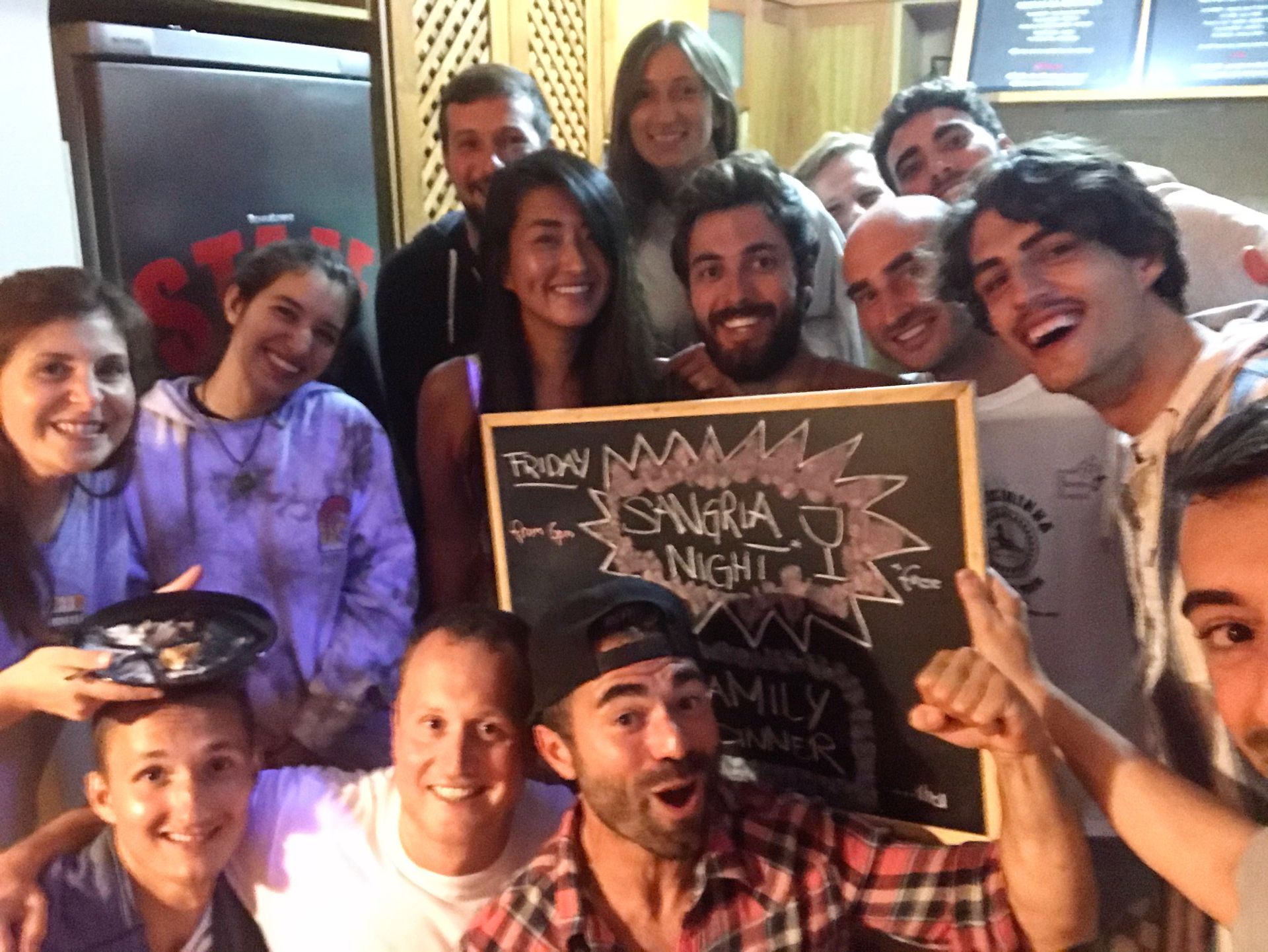 A group of people are posing for a picture and one man is holding a sign that says from espana to night