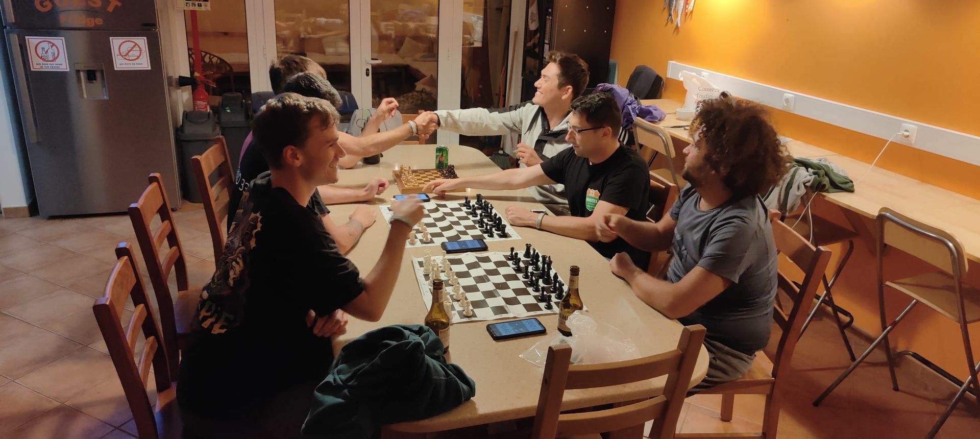 A group of people are sitting at a table playing chess.