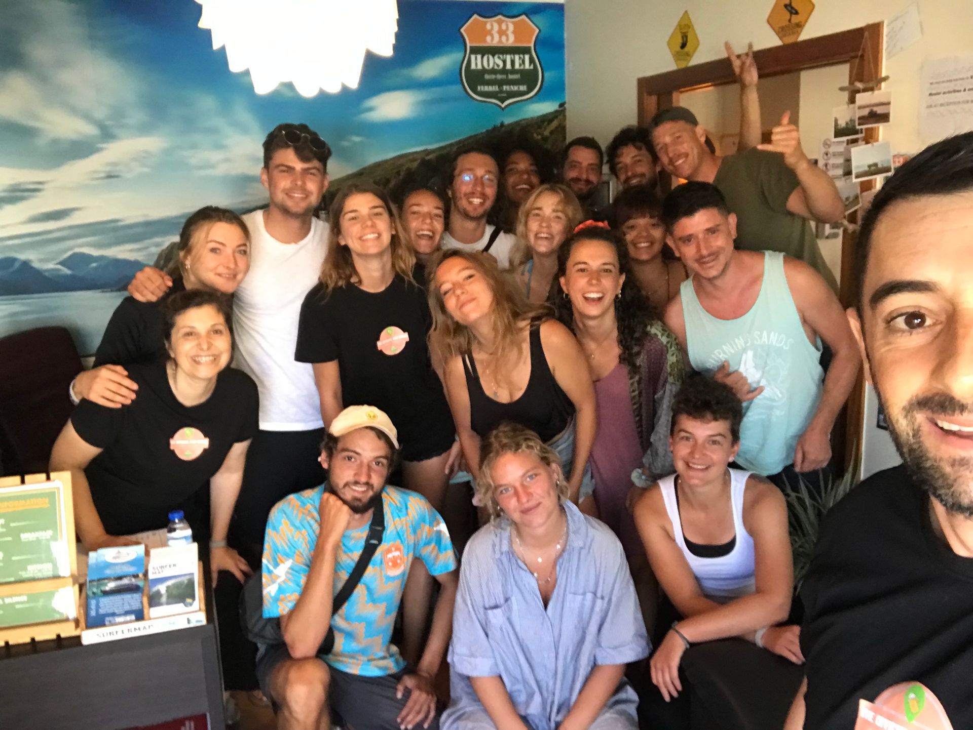 A group of people posing for a picture in front of a sign that says hostel