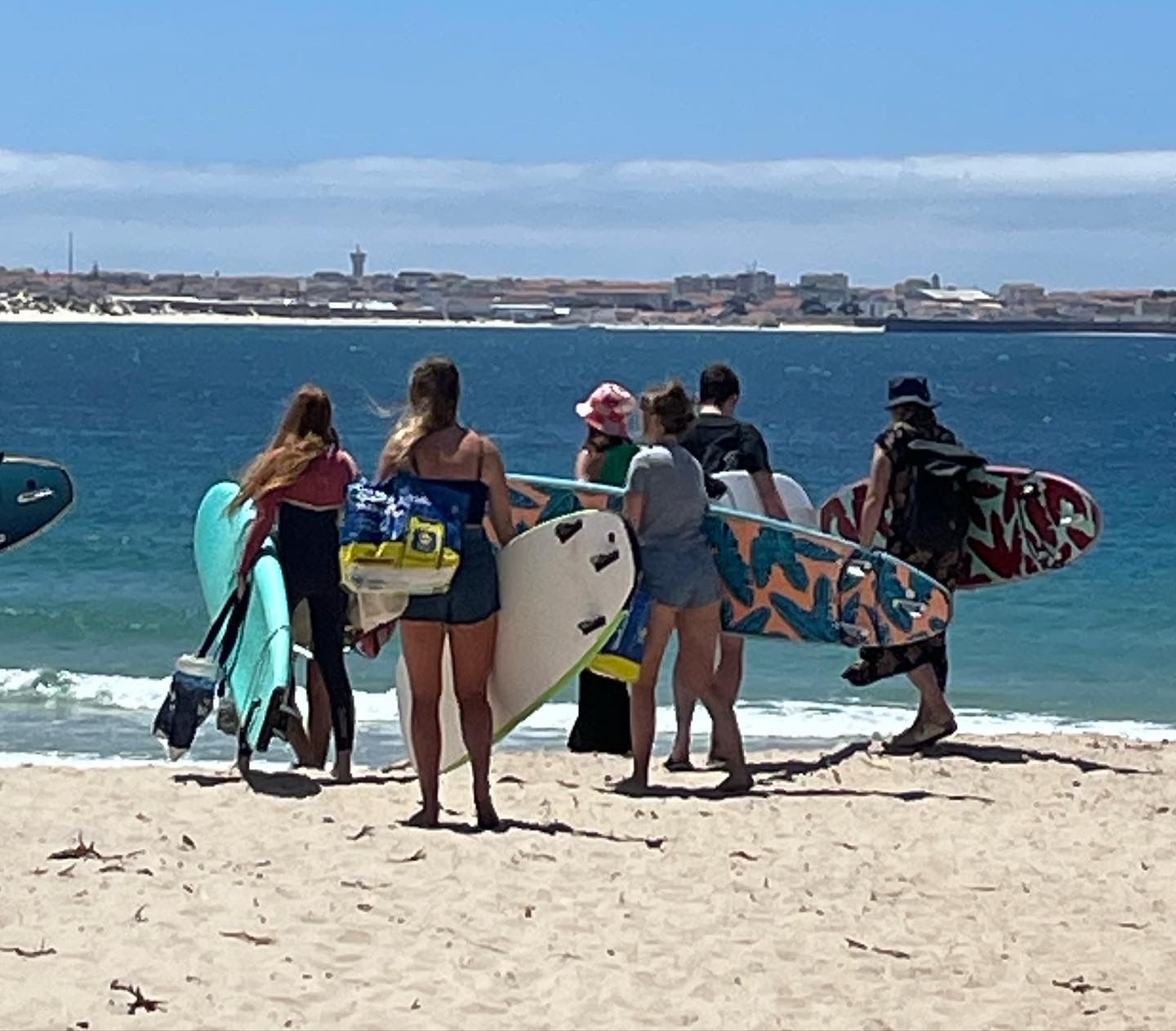 A group of people carrying surfboards on a beach