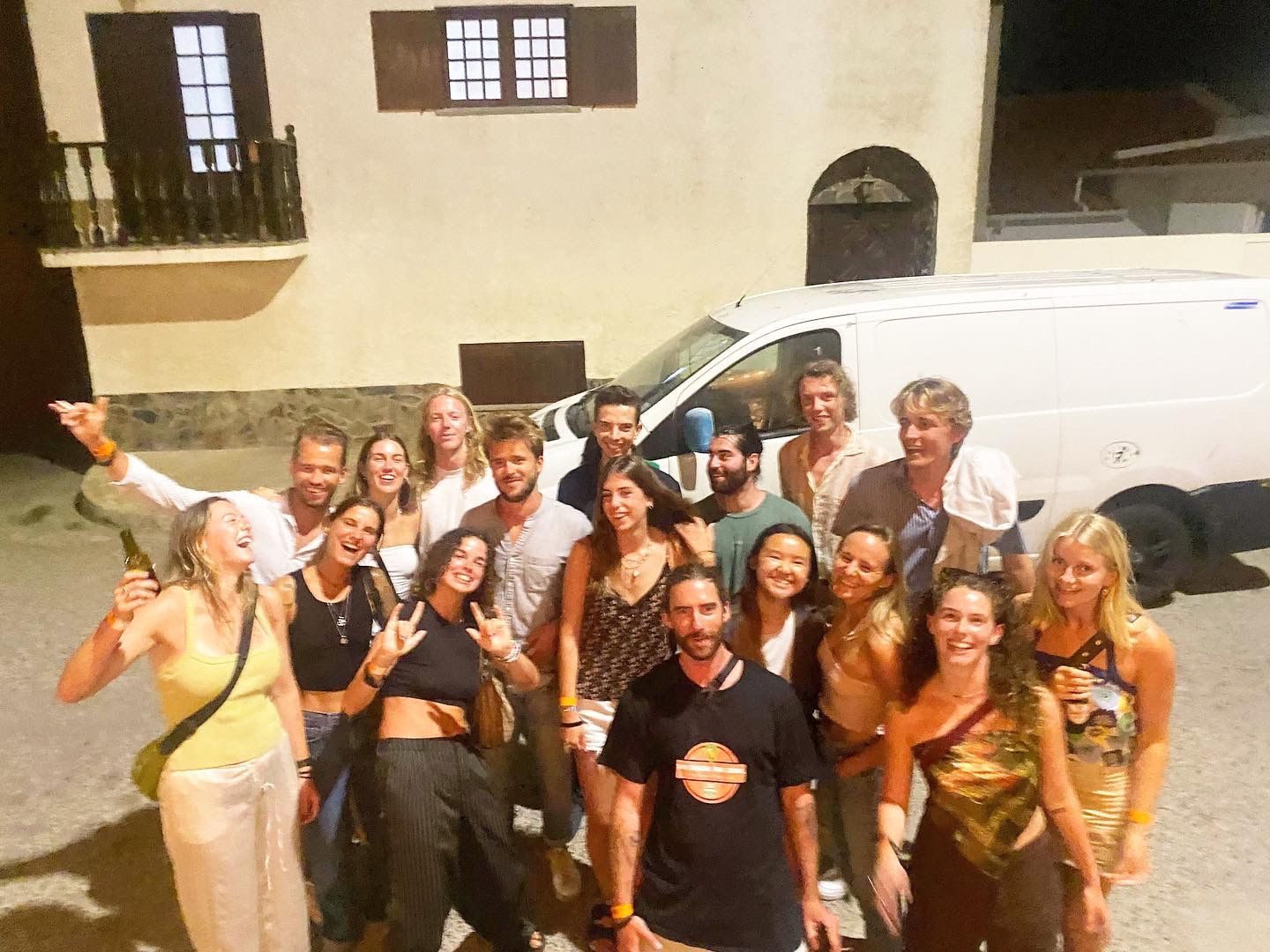 A group of people are posing for a picture in front of a white van.