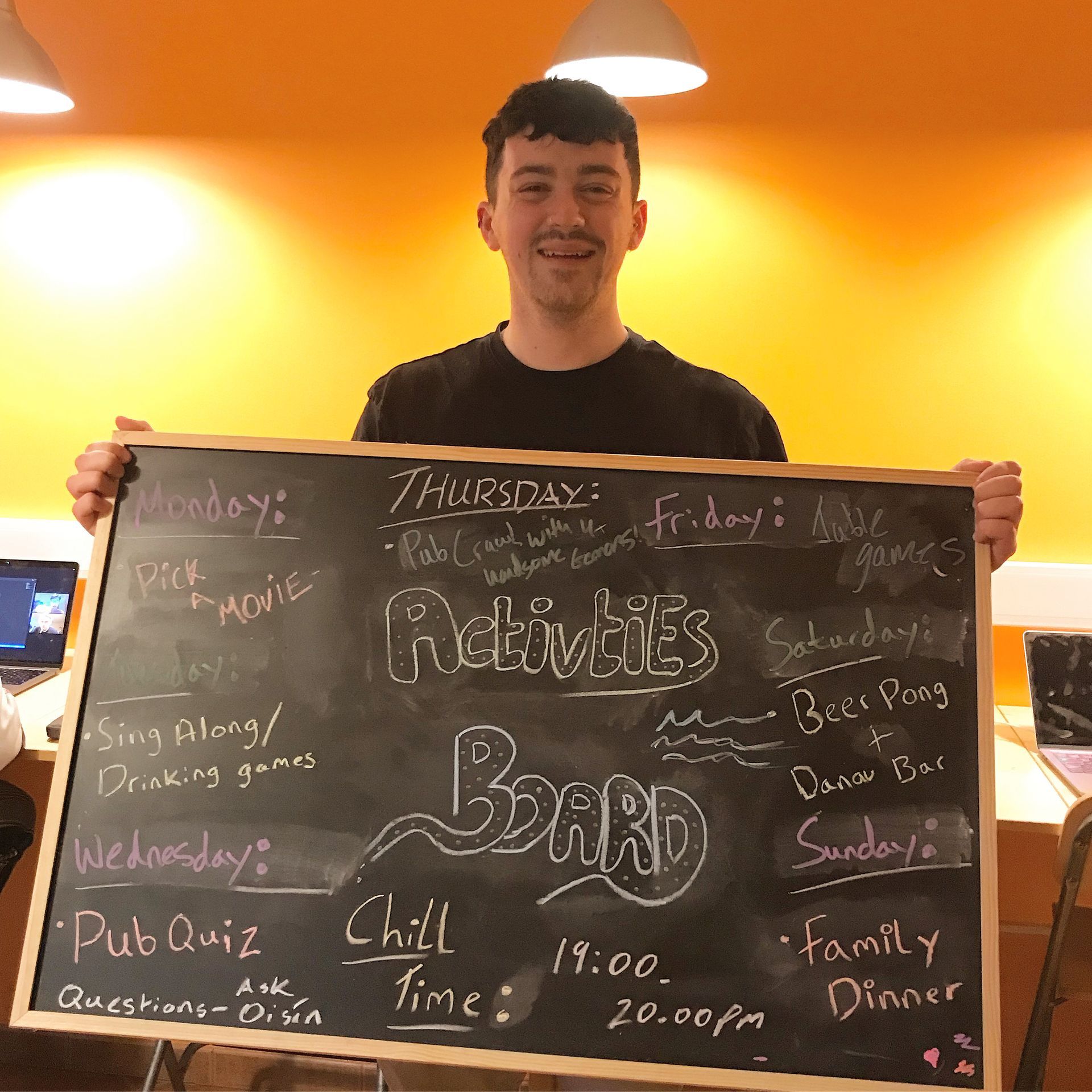 A man is holding a chalkboard with activities written on it