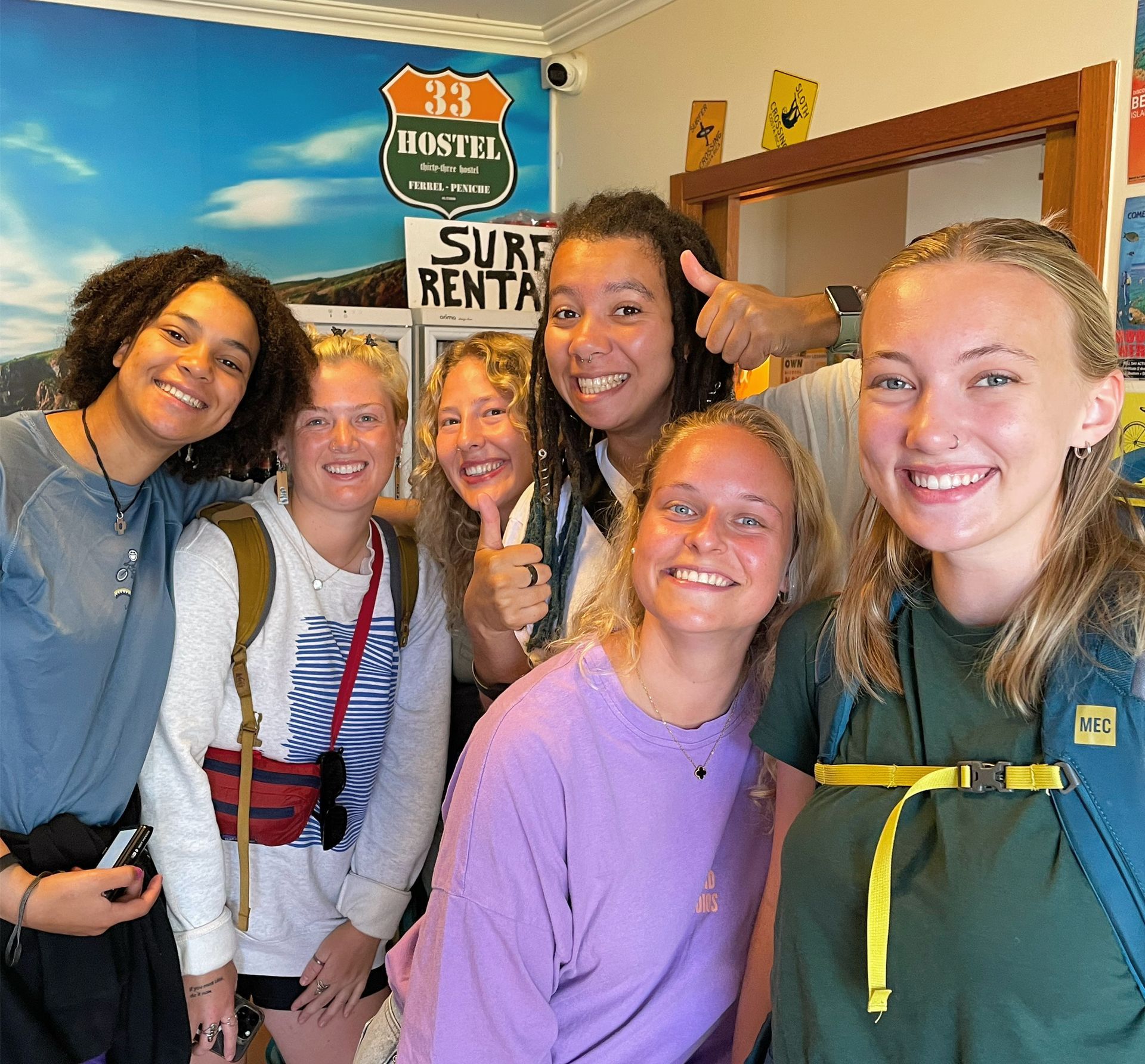 A group of women are posing for a picture in front of a surf rental sign