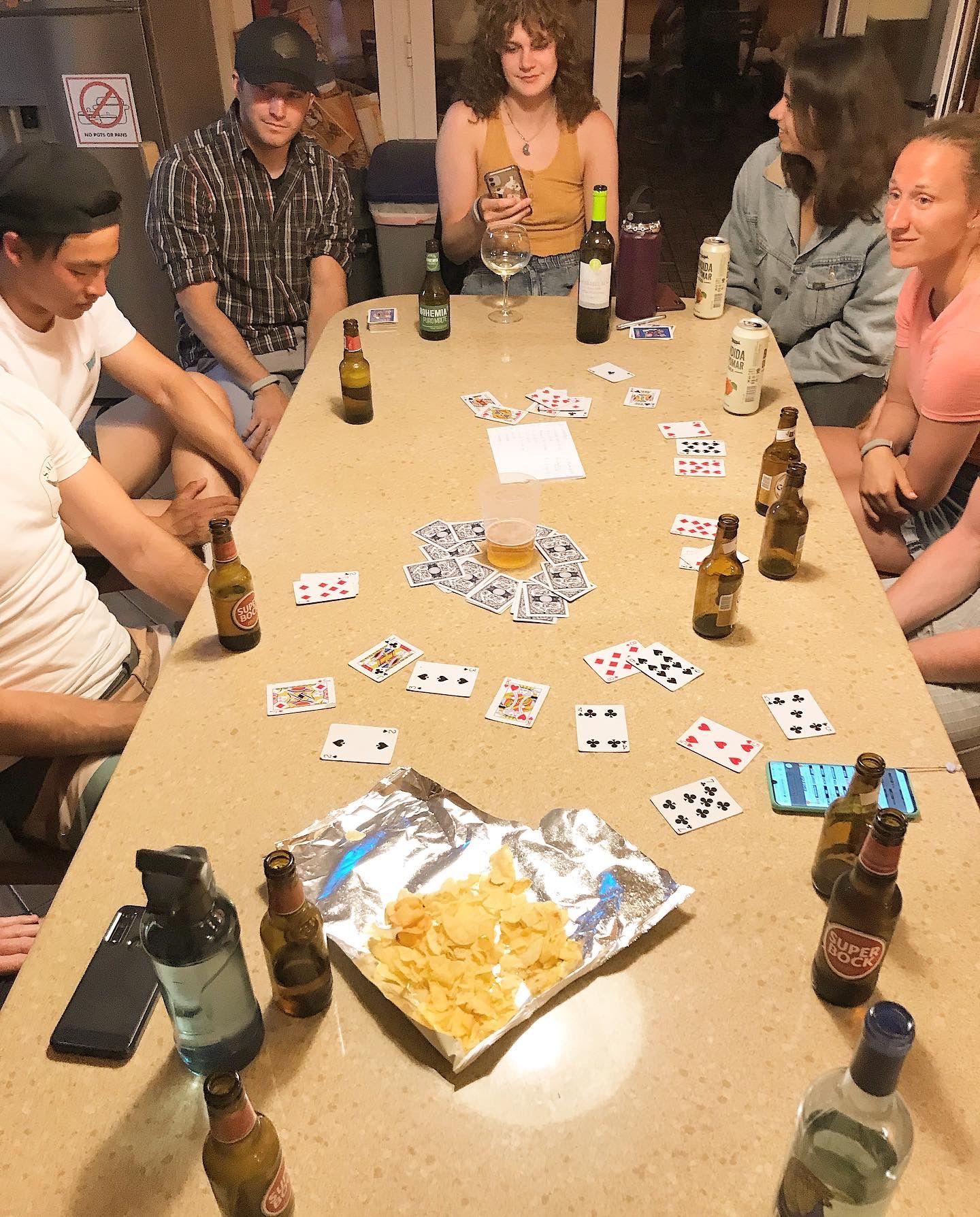 A group of people are sitting around a table with bottles and cards on it