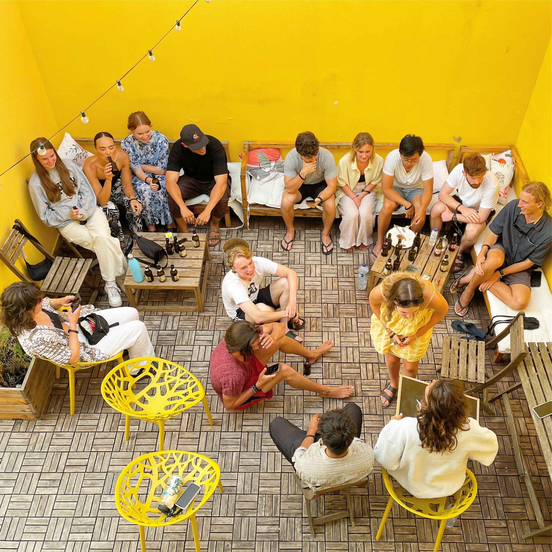 A group of people are sitting in a circle in front of a yellow wall