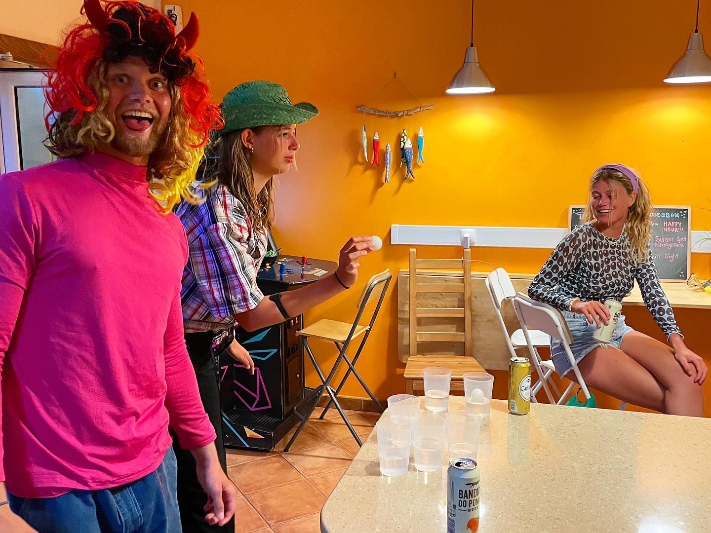 A man in a pink shirt is standing next to two women in costumes.