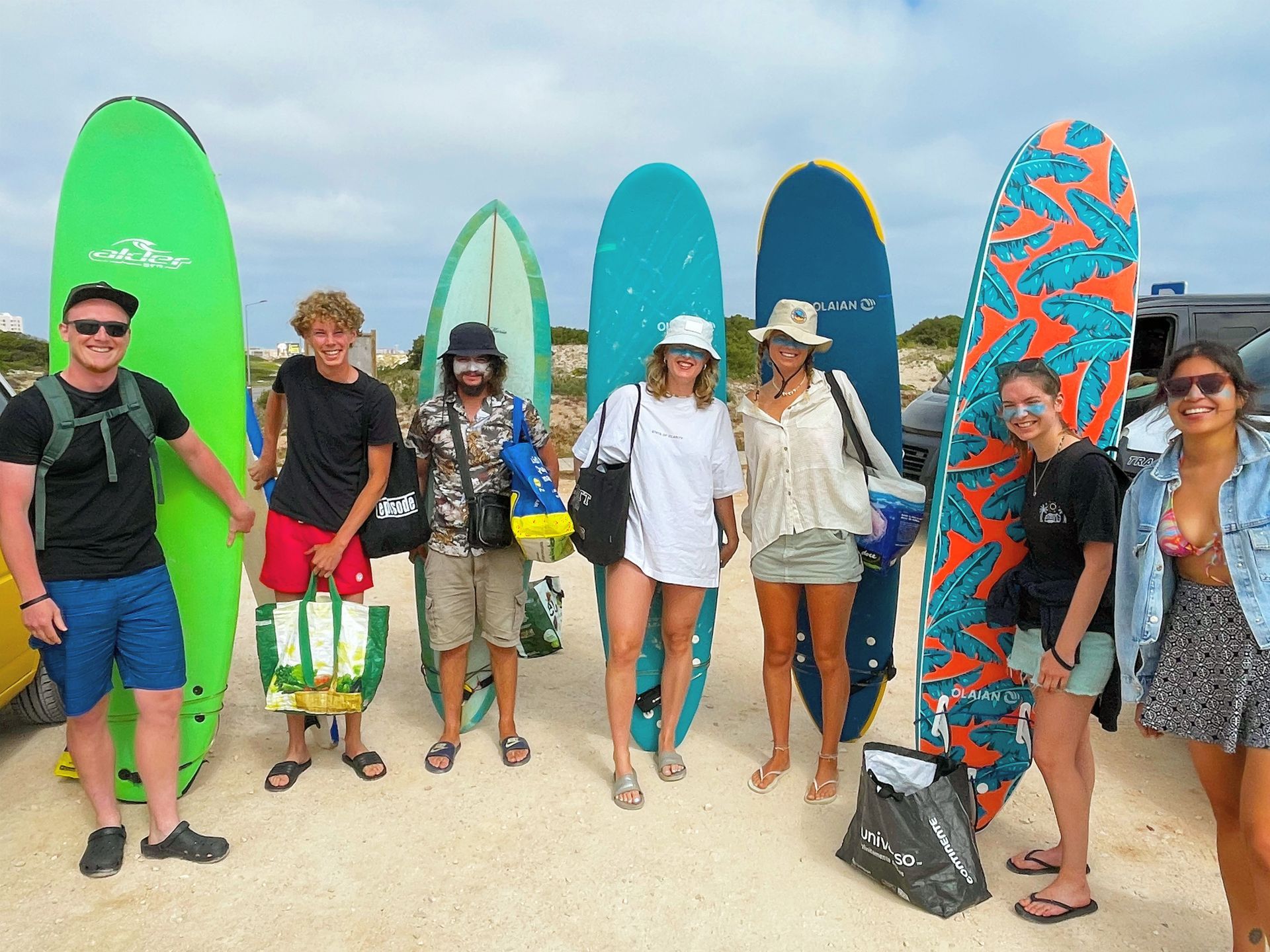 A group of people standing next to surfboards on a beach.