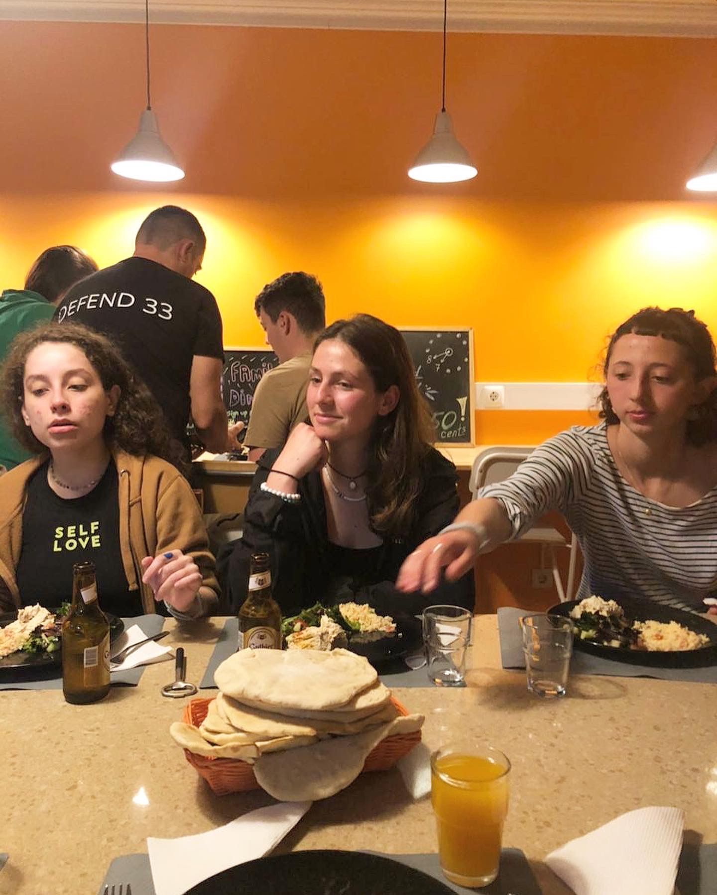 A group of people are sitting at a table with food and drinks.