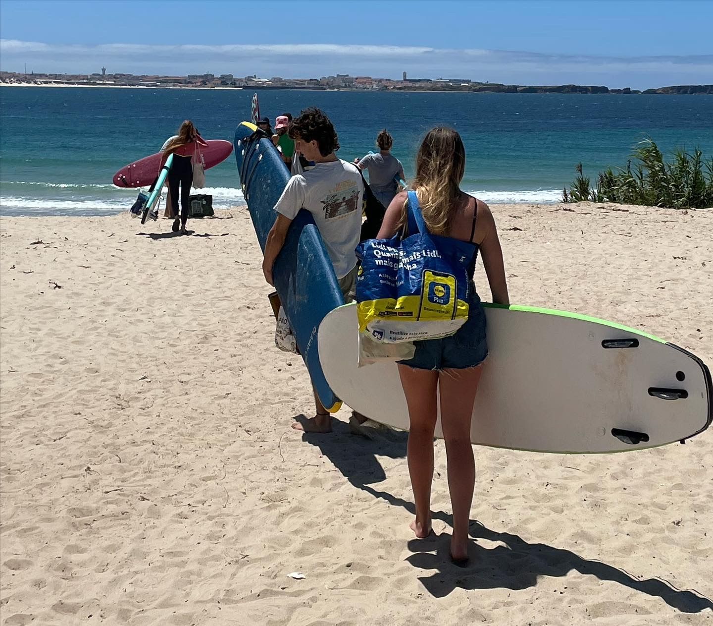 A woman is carrying a surfboard on the beach