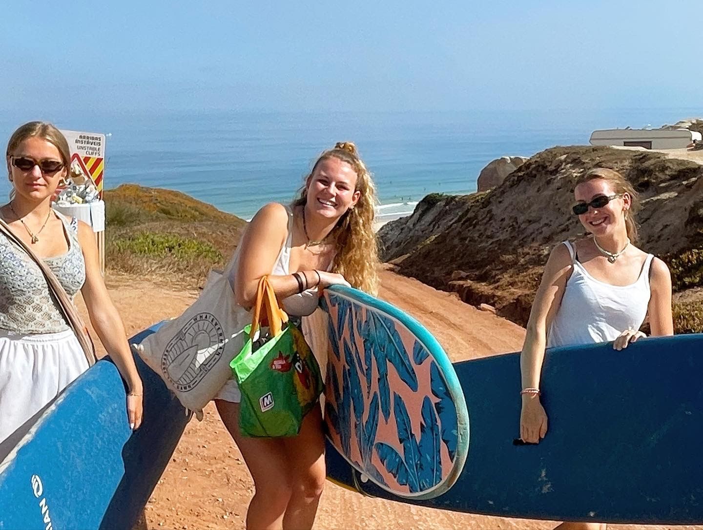 Three women are holding surfboards in front of the ocean
