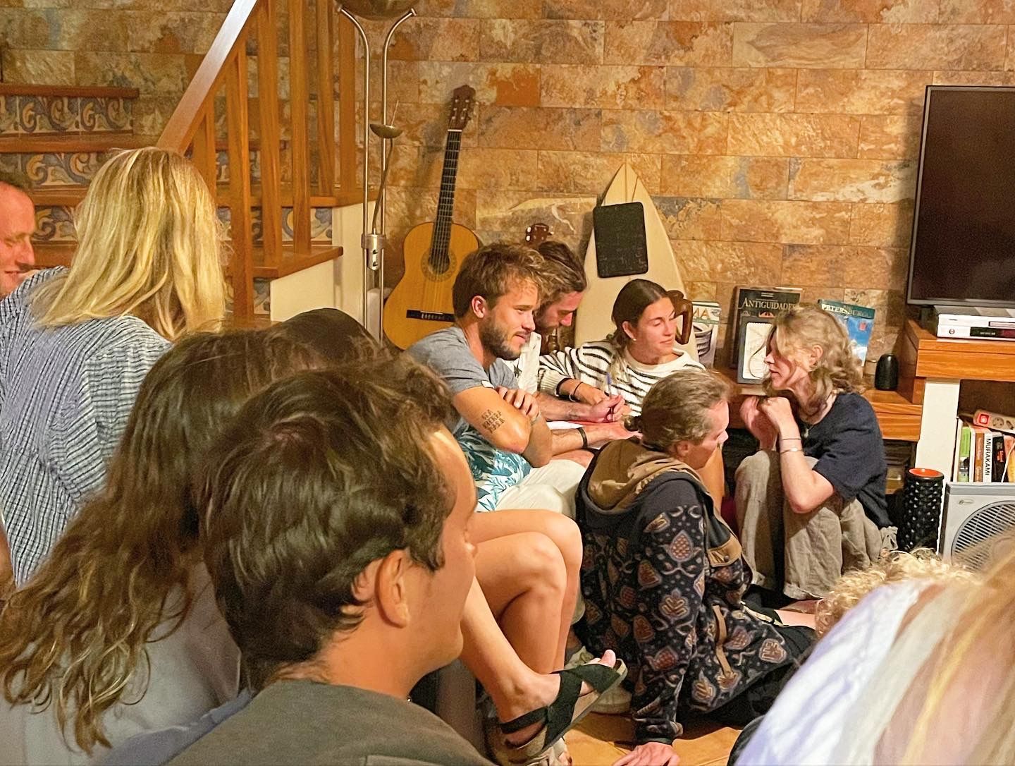 A group of people are sitting on the floor in a living room.