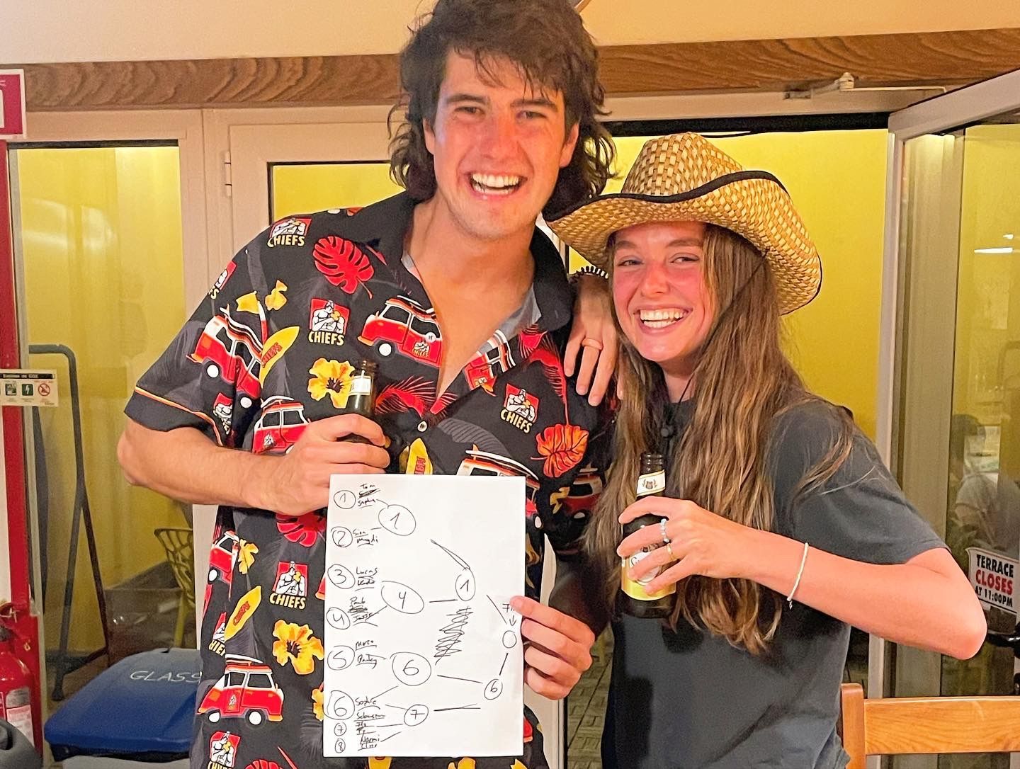 A man and a woman are posing for a picture while the man is holding a drawing.