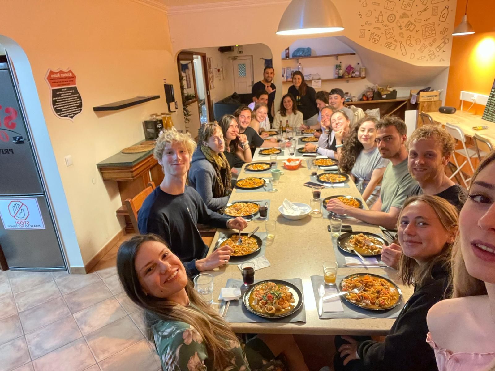 A group of people are sitting at a long table eating pizza.