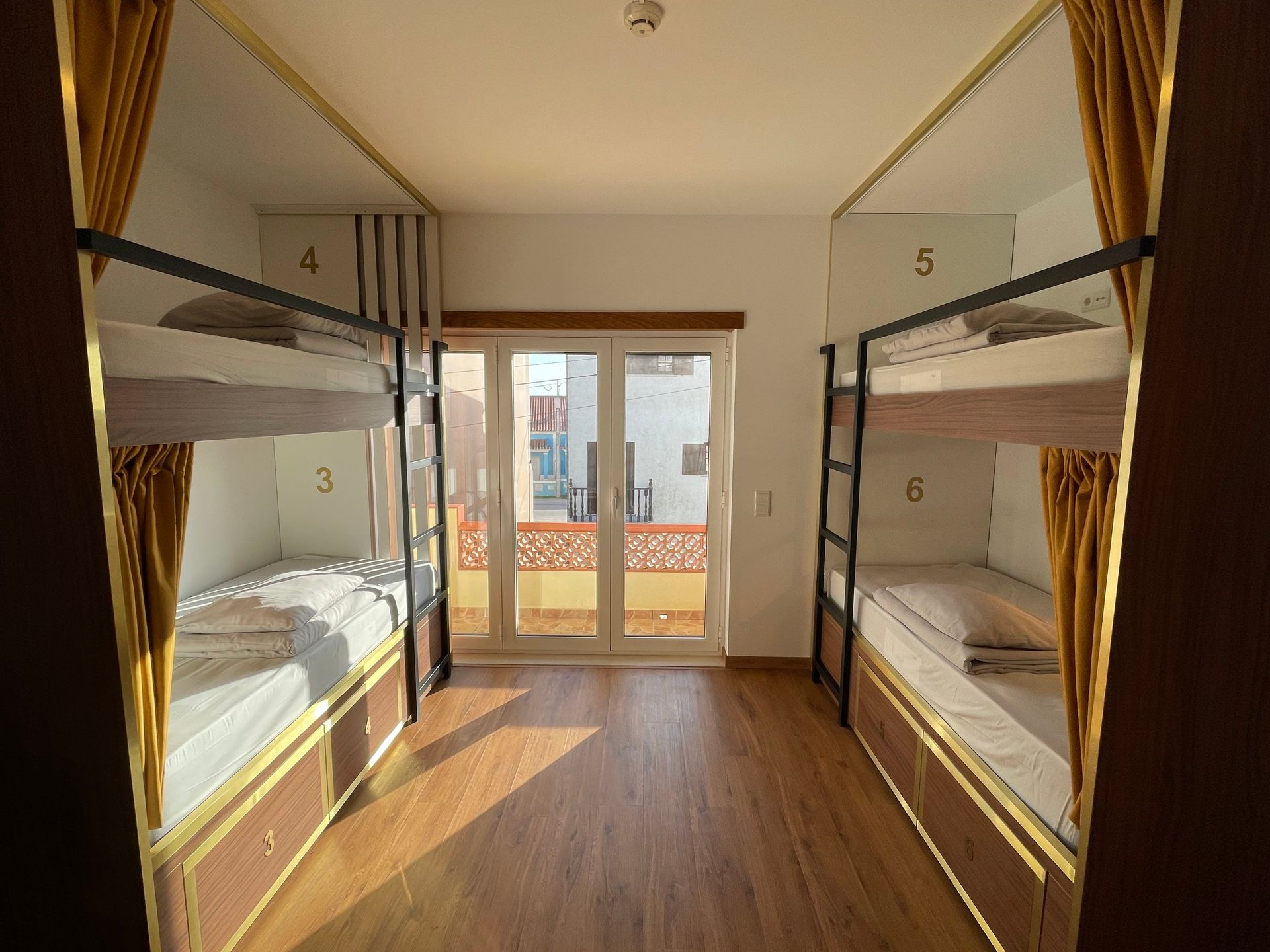 A bunk bed room with four bunk beds and a balcony.