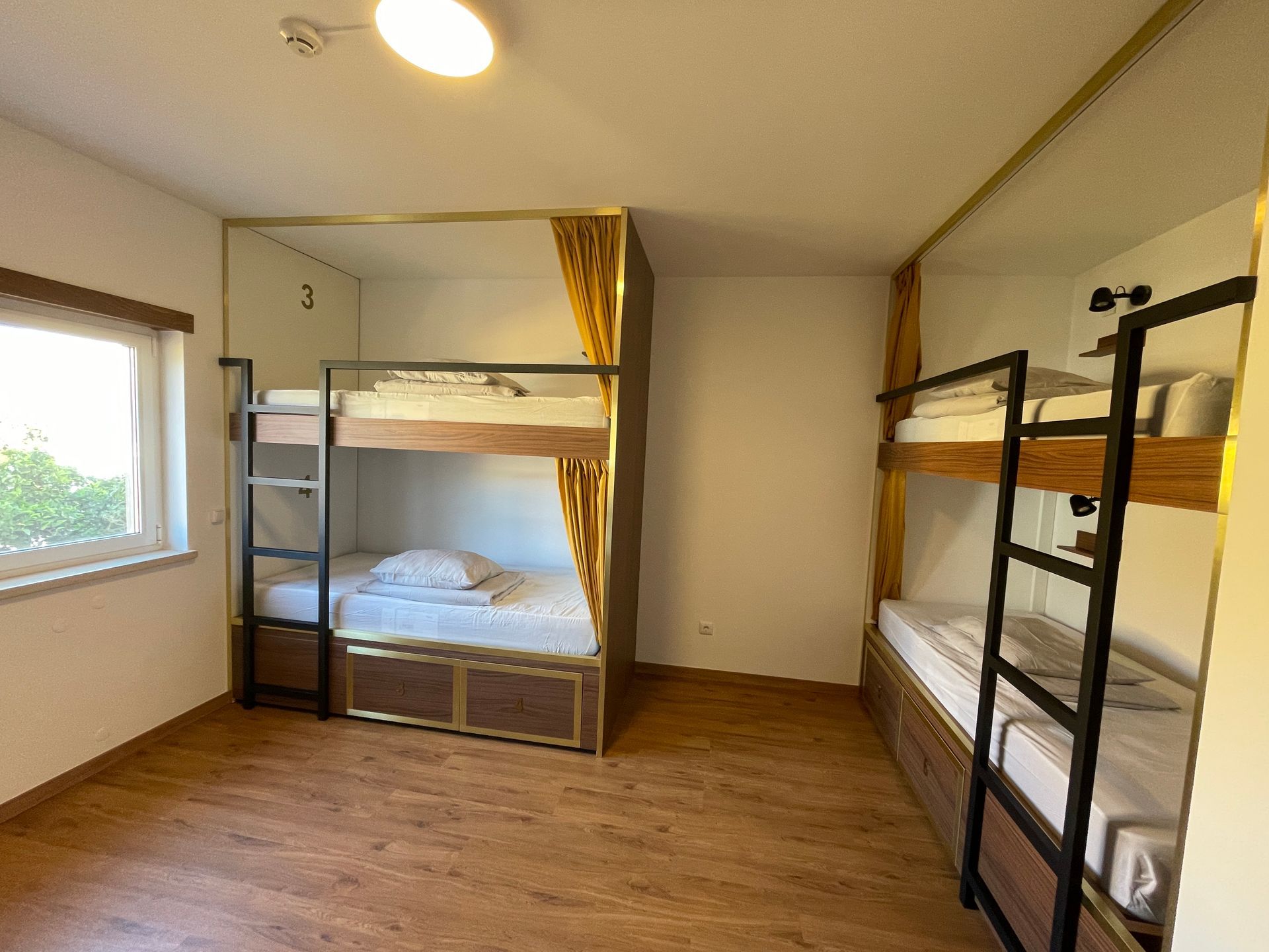 A room with three bunk beds and a window.