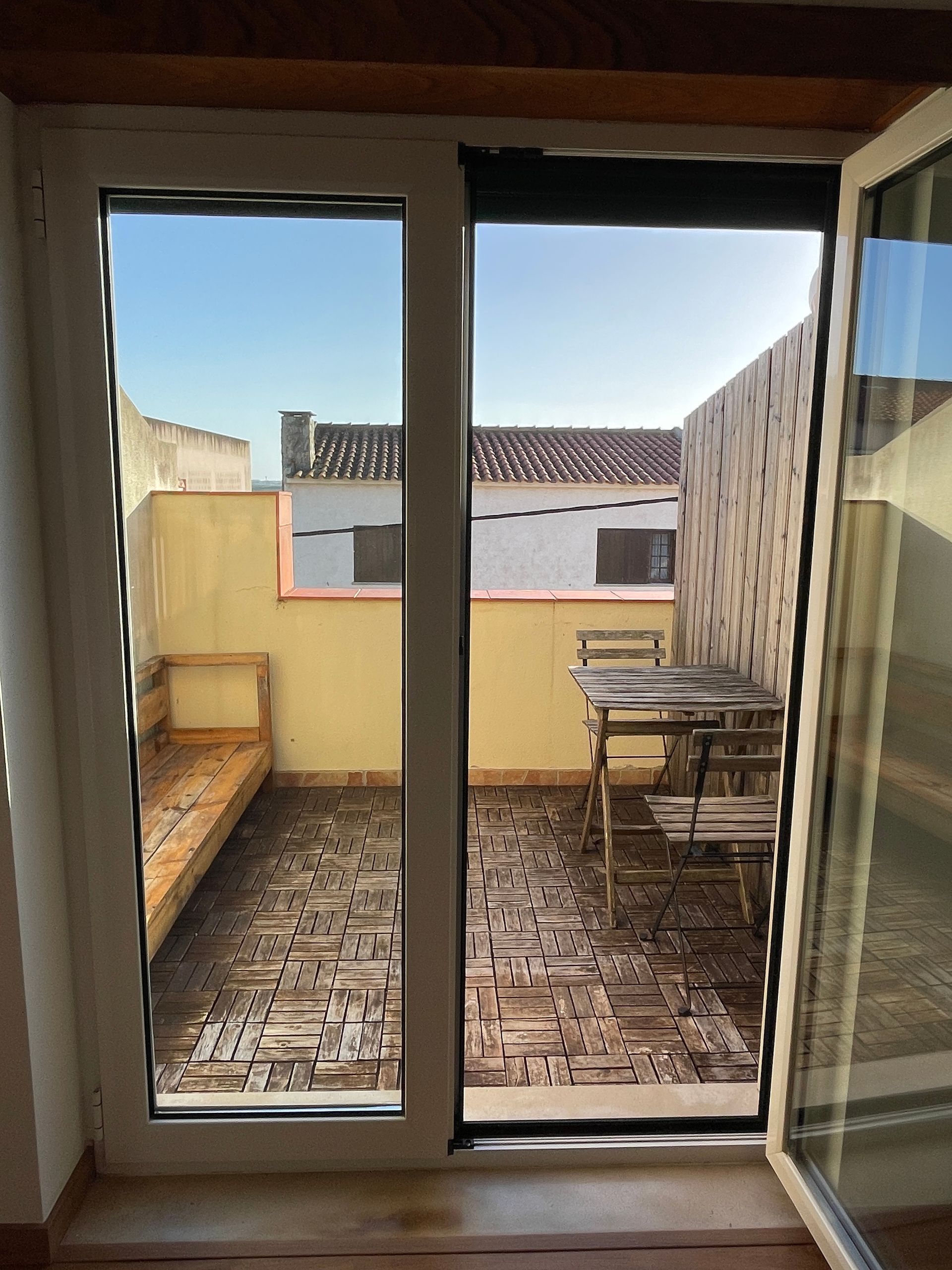 A balcony with a table and chairs is visible through a sliding glass door