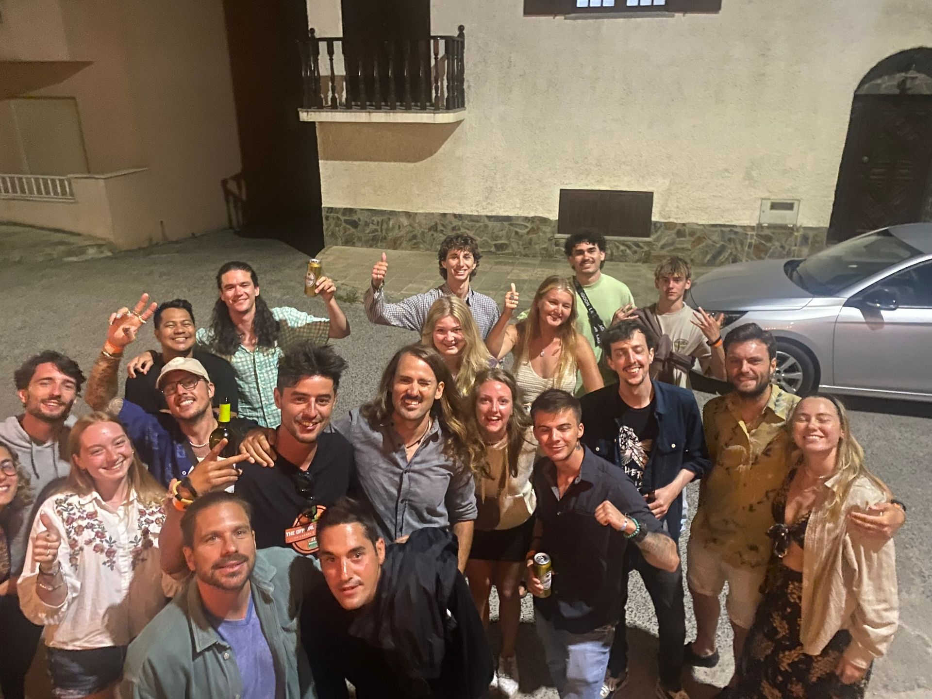 A group of people posing for a picture in front of a car