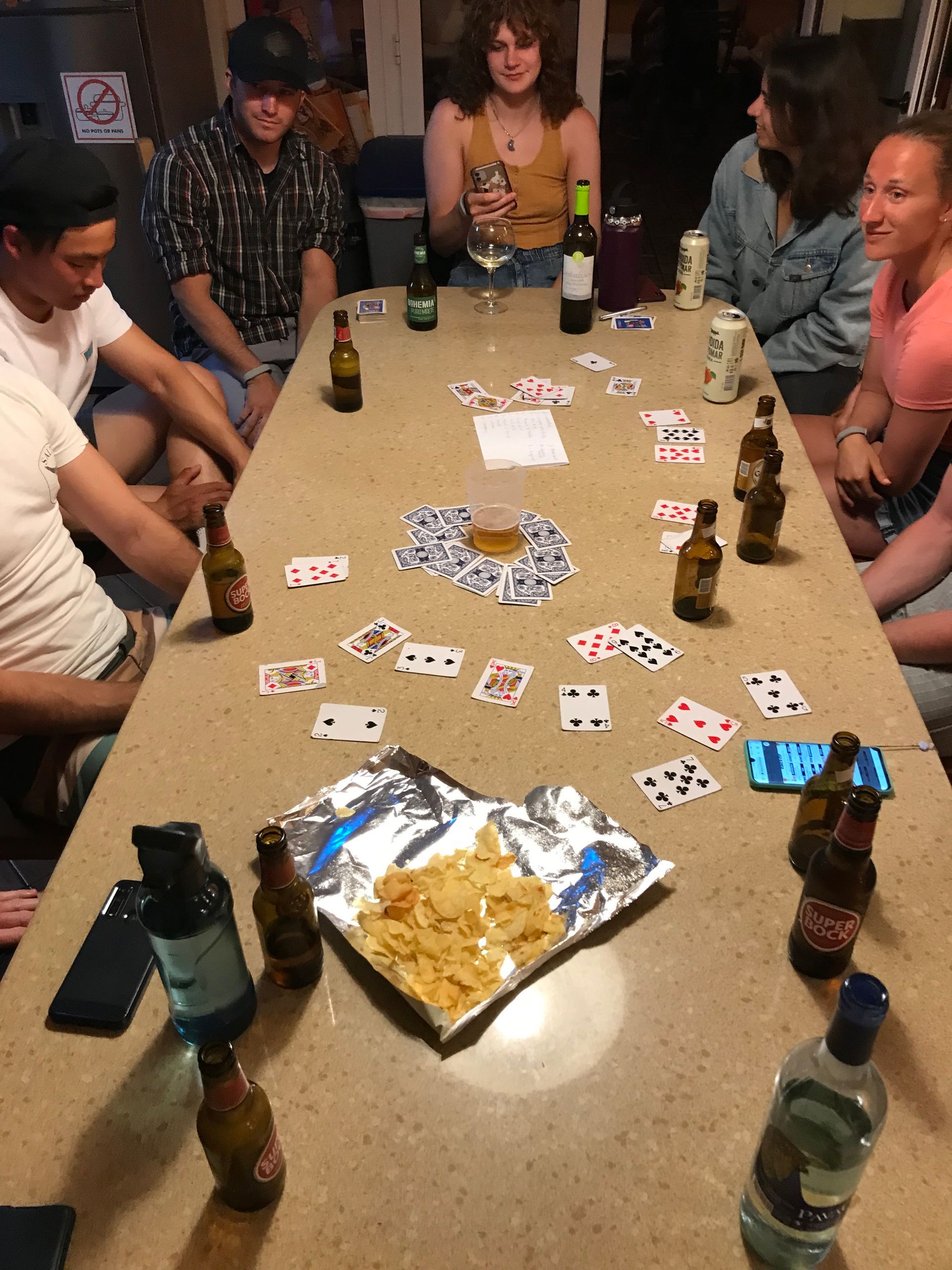 A group of people are sitting around a table playing a game of cards