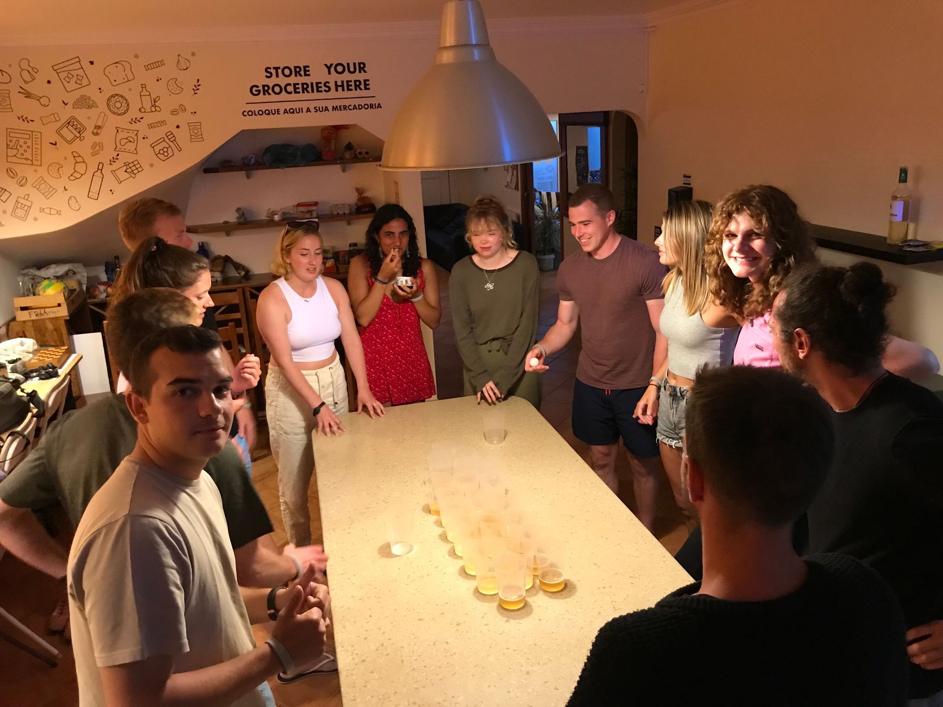 A group of people are standing around a table in a kitchen.