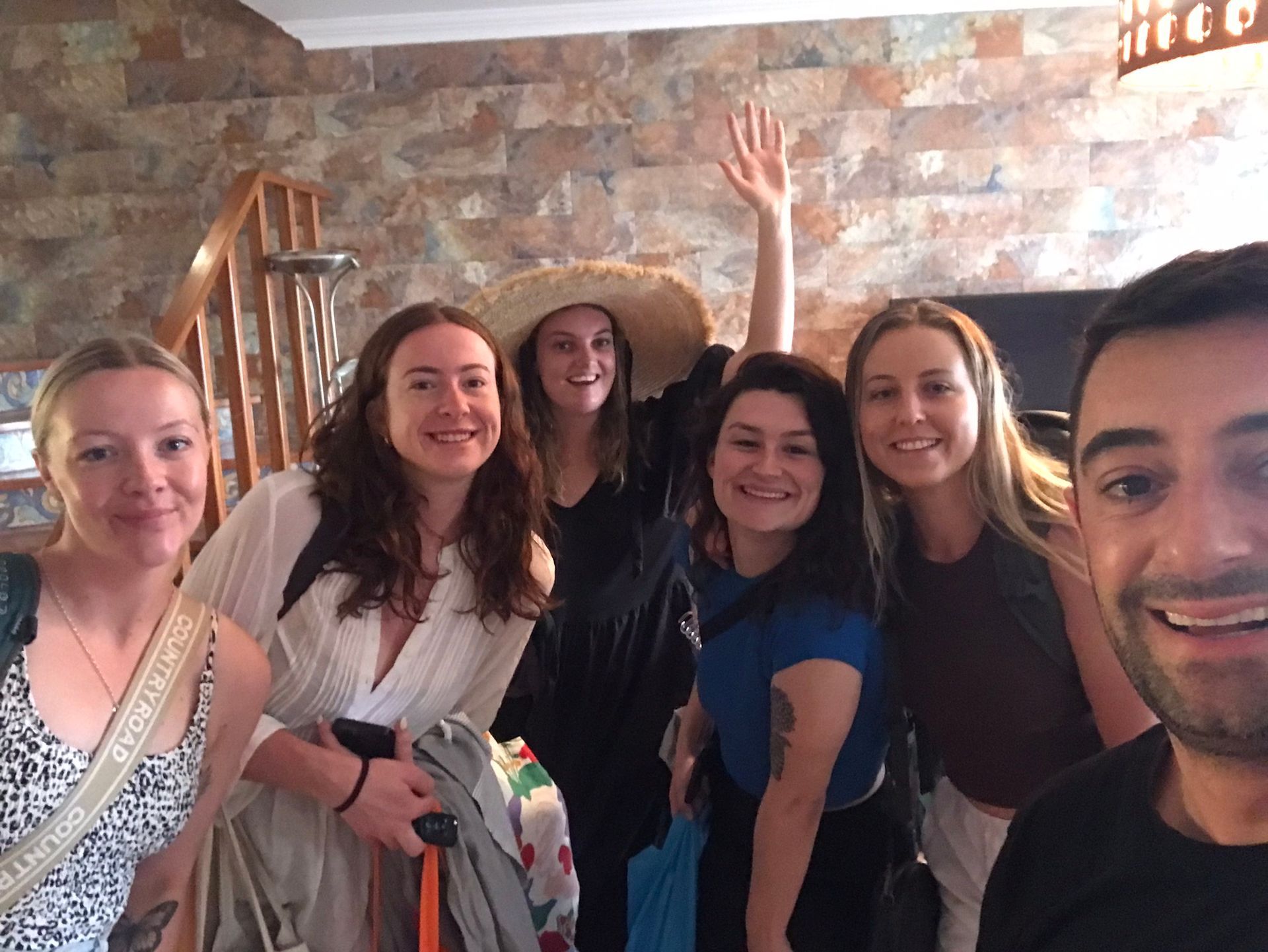 A group of people posing for a picture with one woman wearing a hat