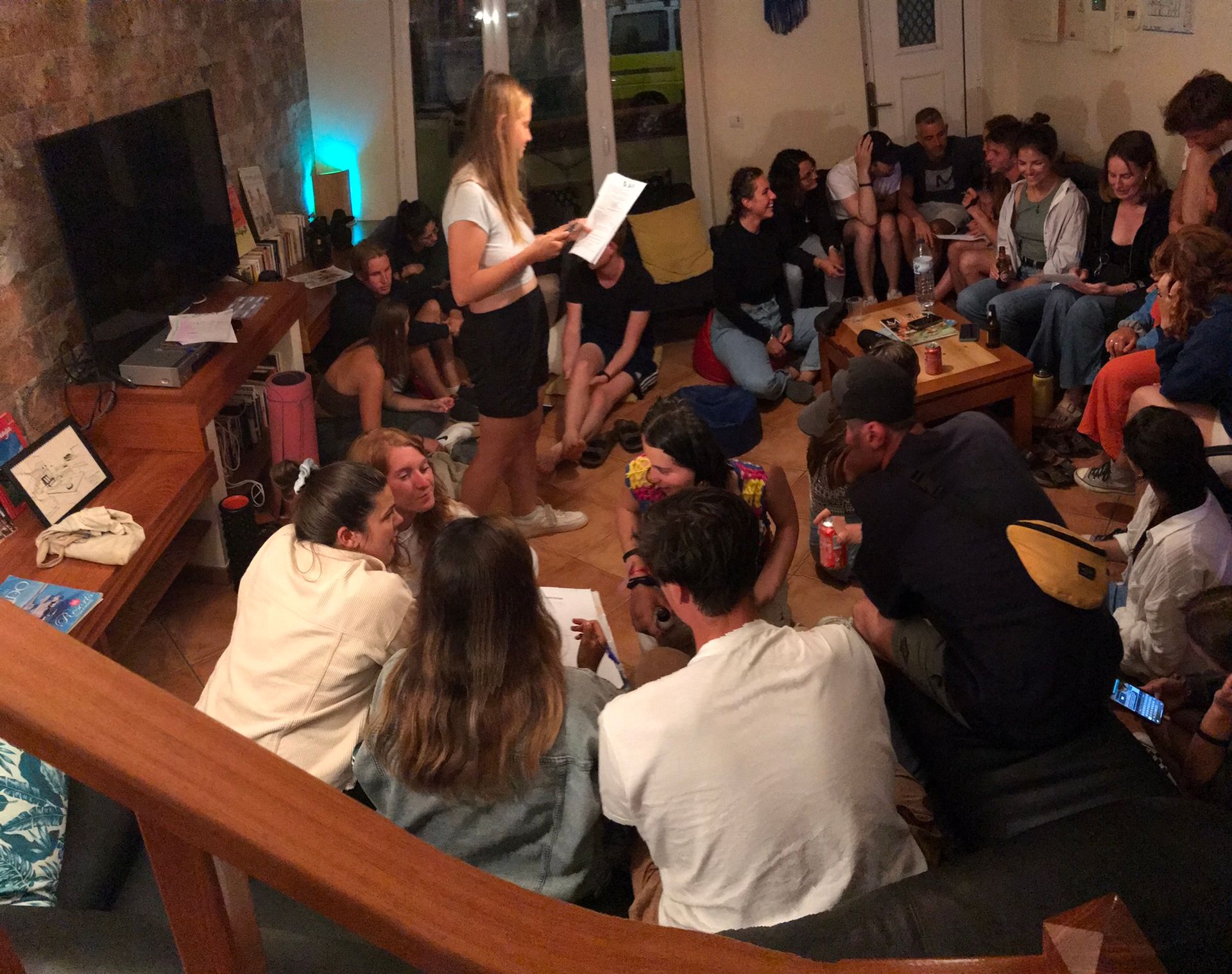 A woman is giving a presentation to a group of people in a living room.