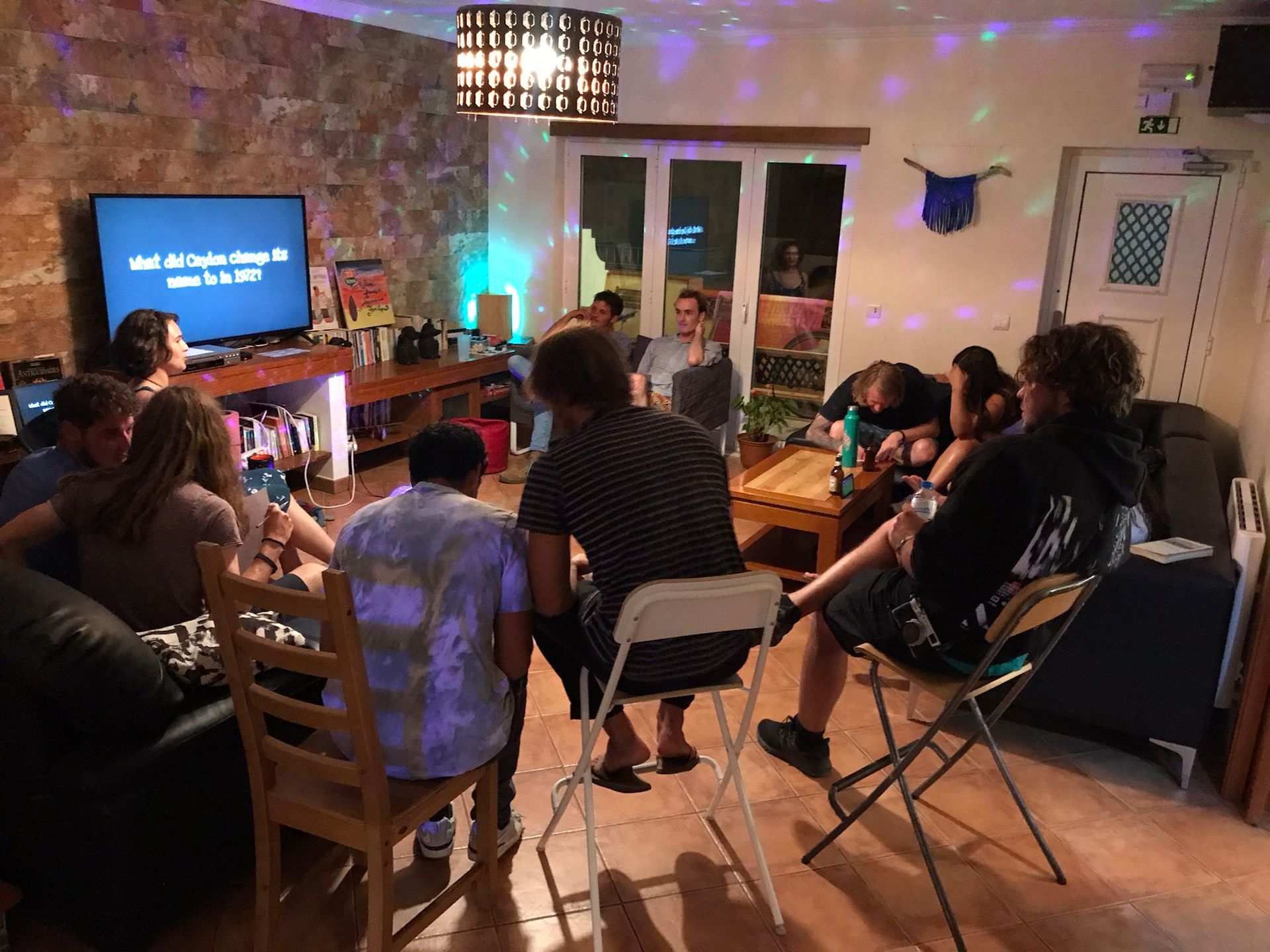 A group of people are sitting in a living room watching a television.
