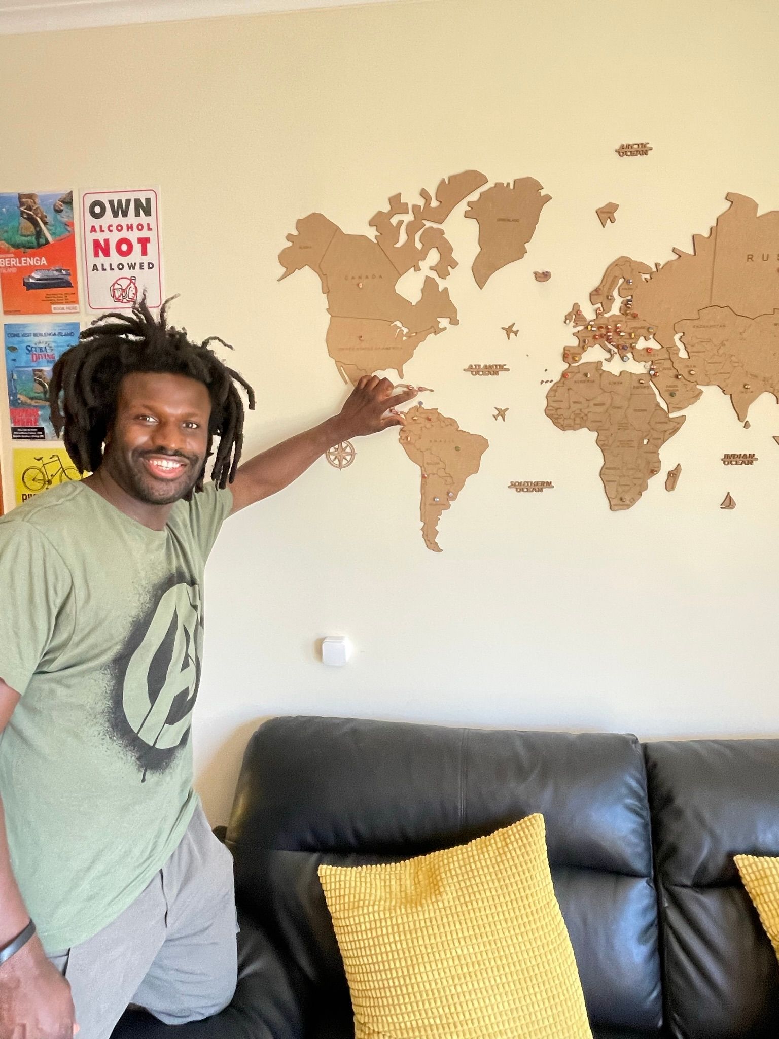 A man is standing in front of a map of the world on a wall.