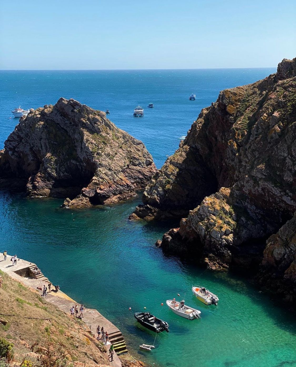 A group of boats are floating in a body of water surrounded by rocks