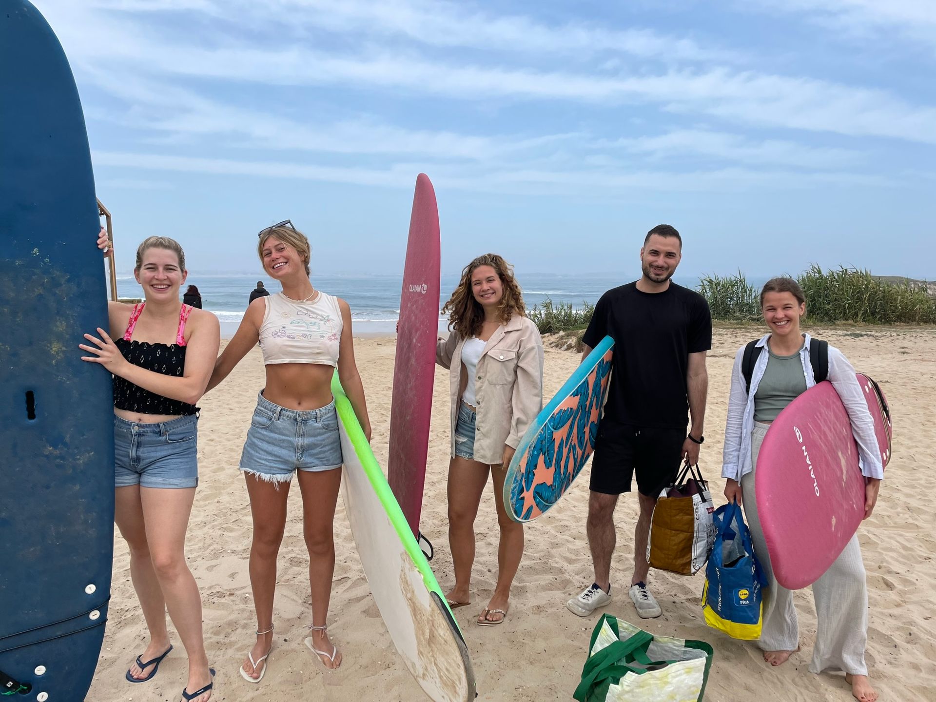 A group of people standing on a beach holding surfboards.
