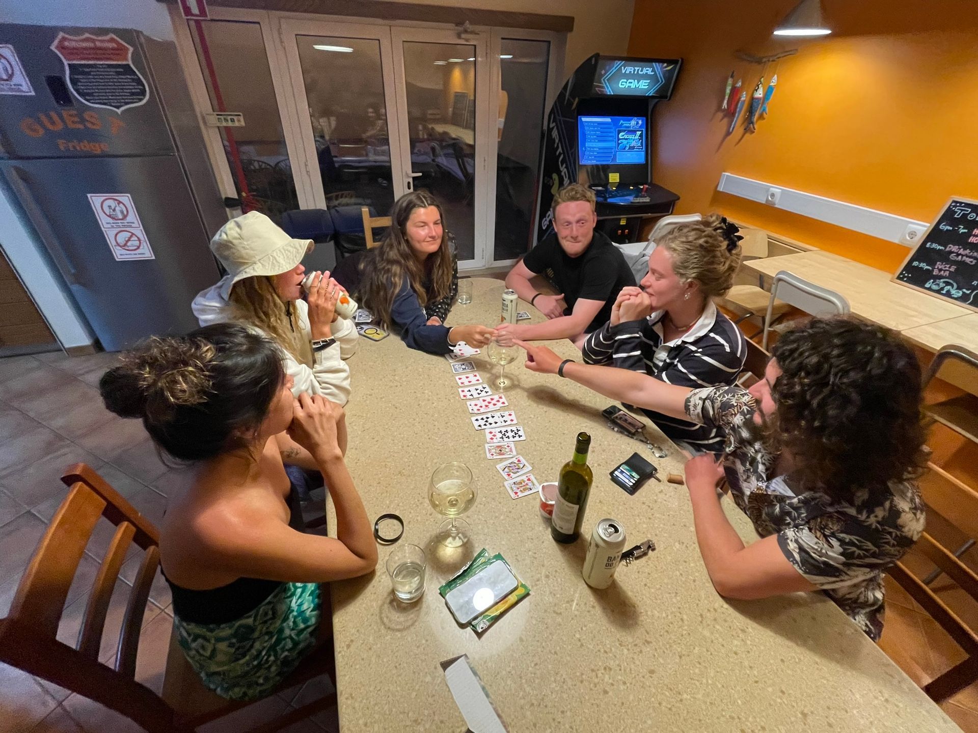 A group of people are sitting around a table playing cards.