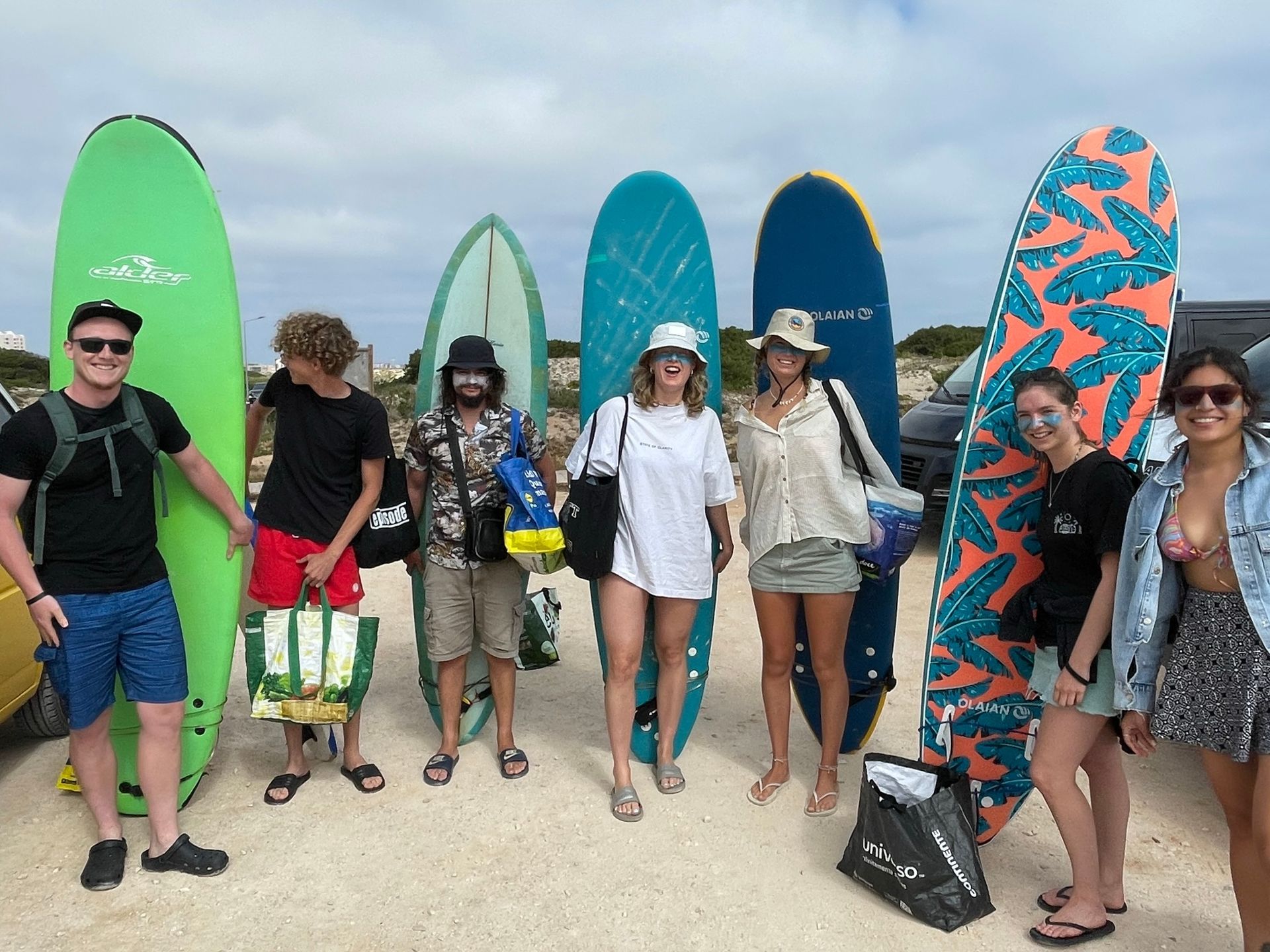 A group of people standing next to surfboards on a beach.