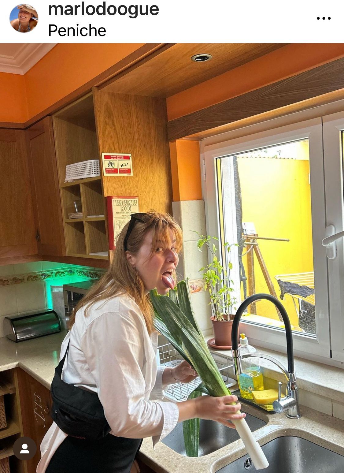 A woman is holding a large green vegetable in her hand in a kitchen.