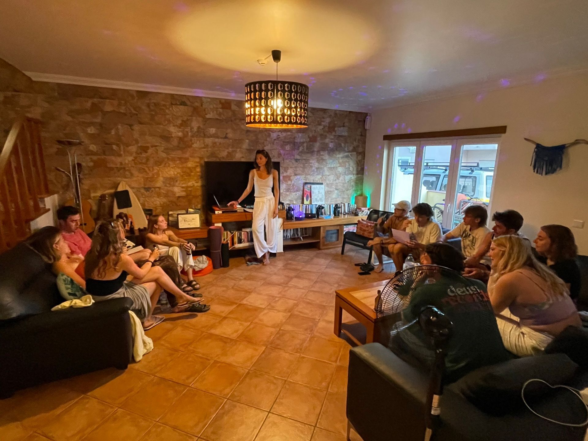 A group of people are sitting around a table in a living room.