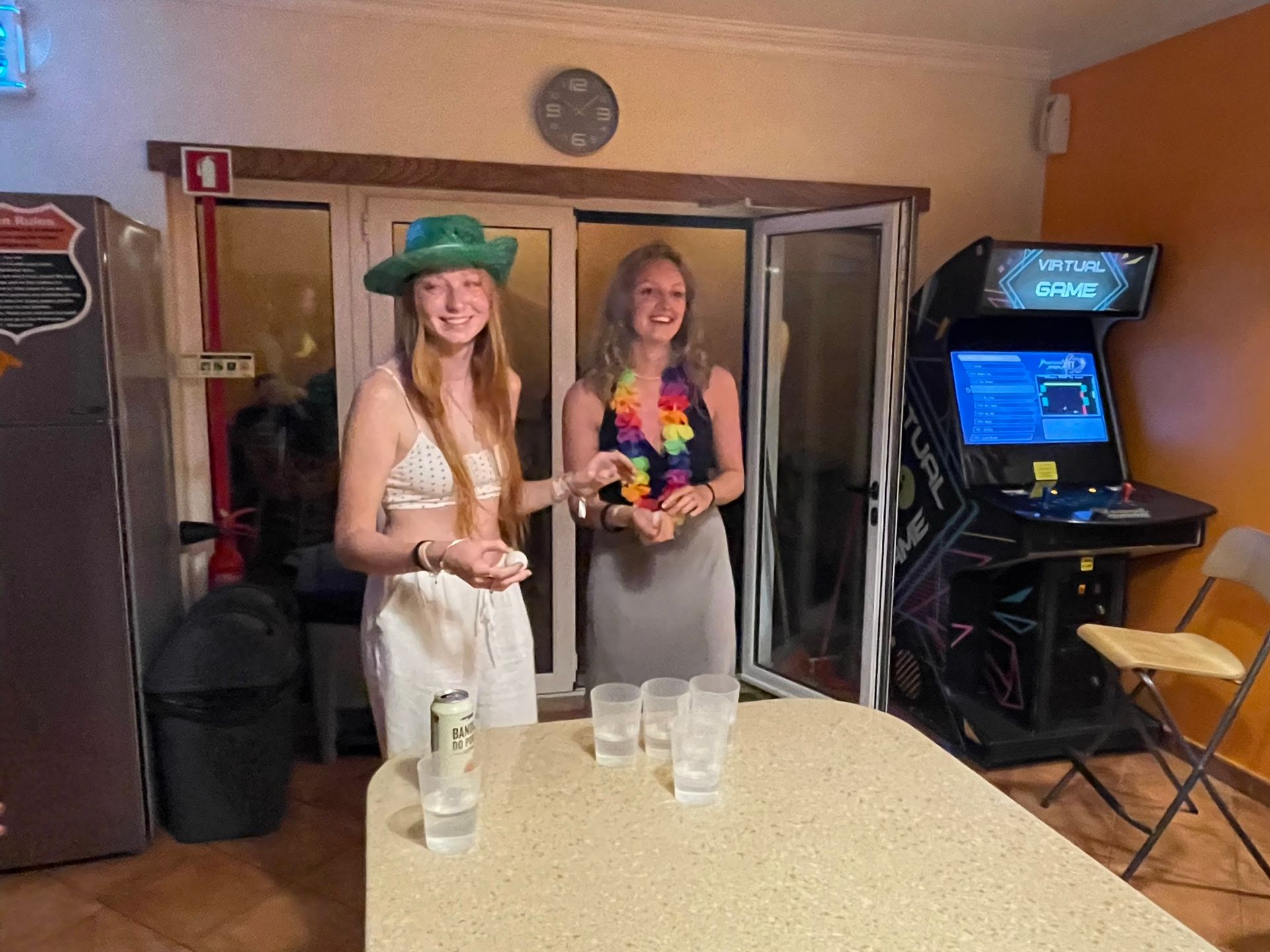 Two women are standing next to a table with glasses and a can of beer.