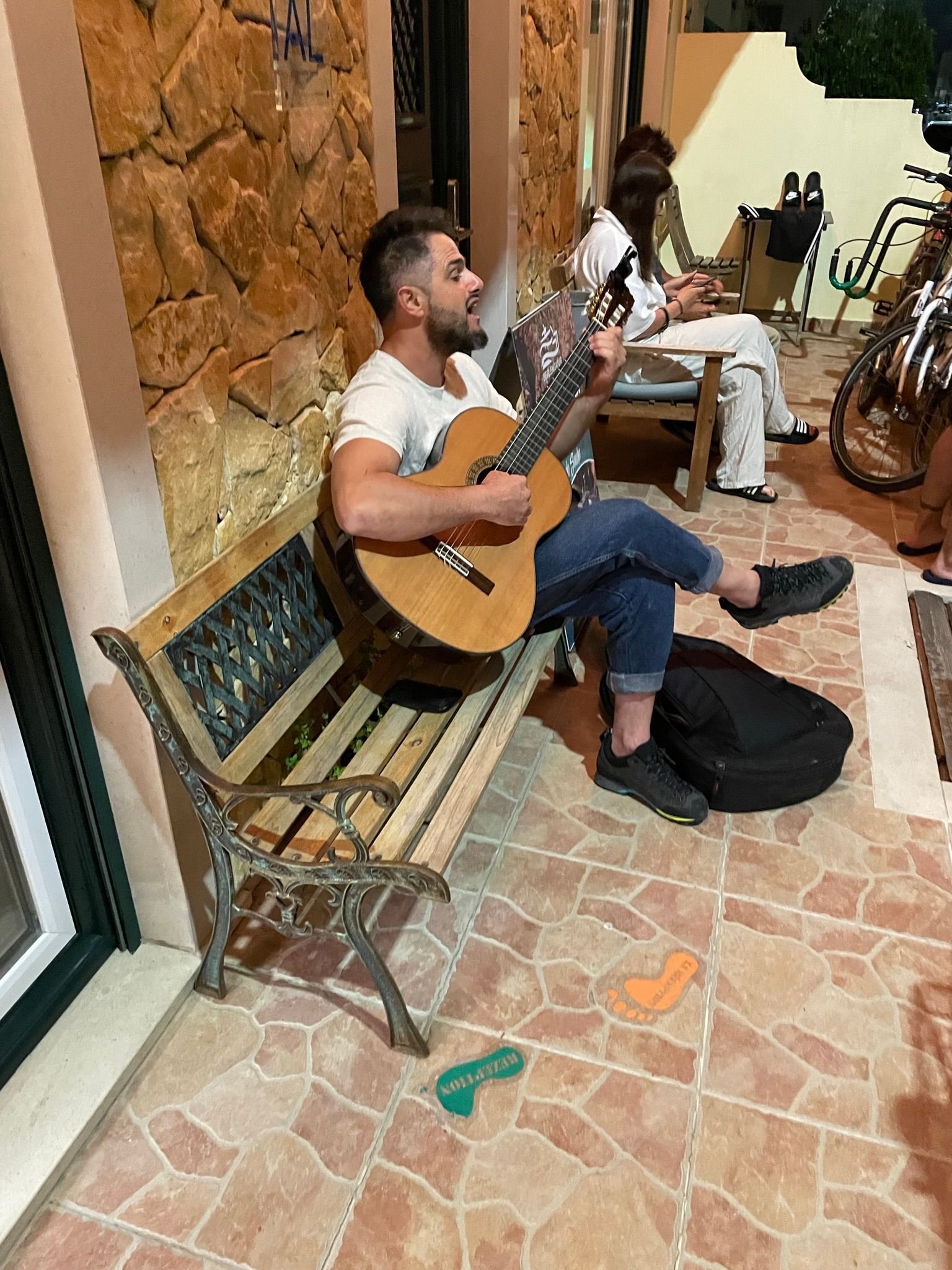 A man is sitting on a bench playing a guitar.