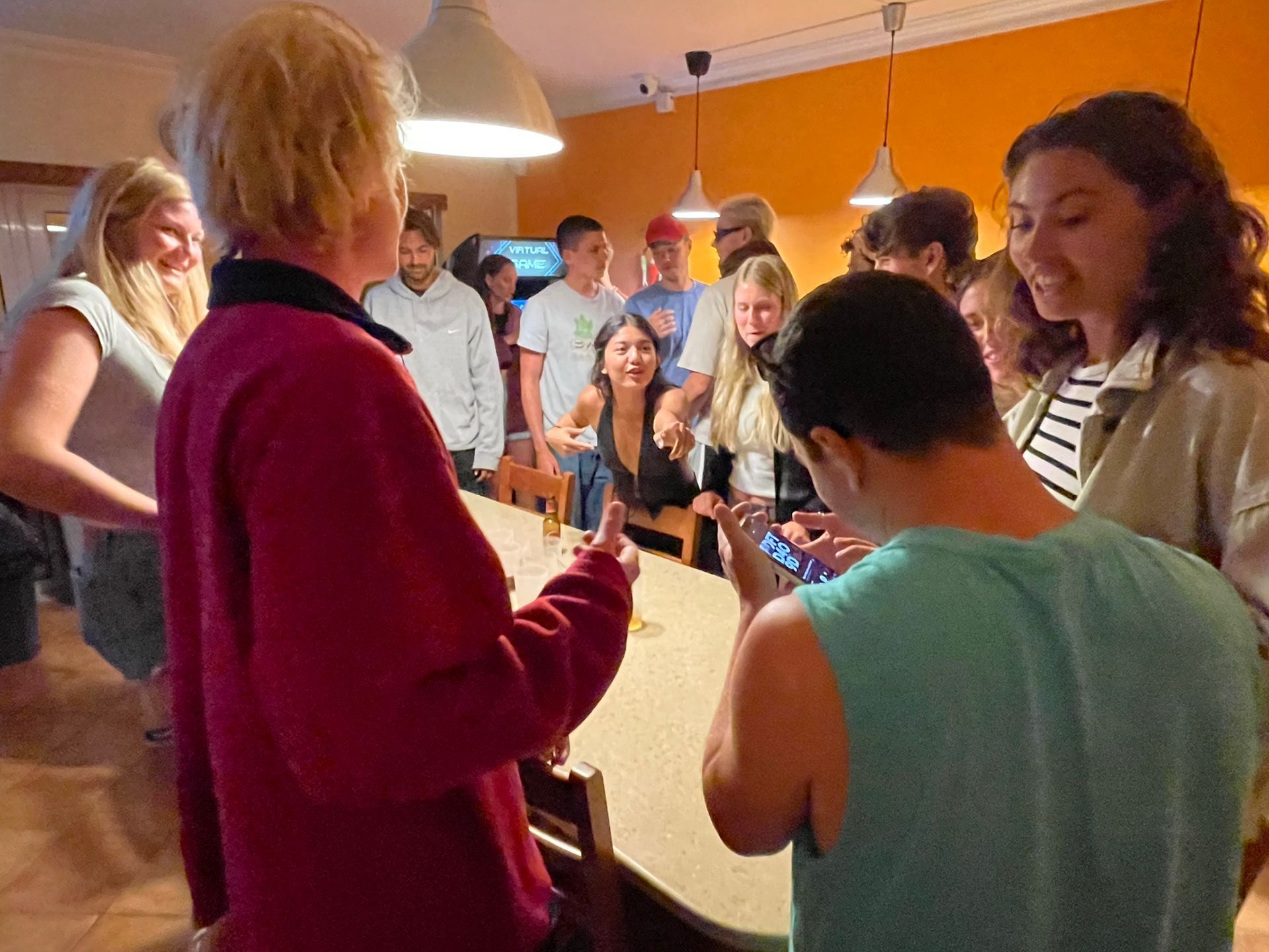 A group of people are standing around a table talking to each other.