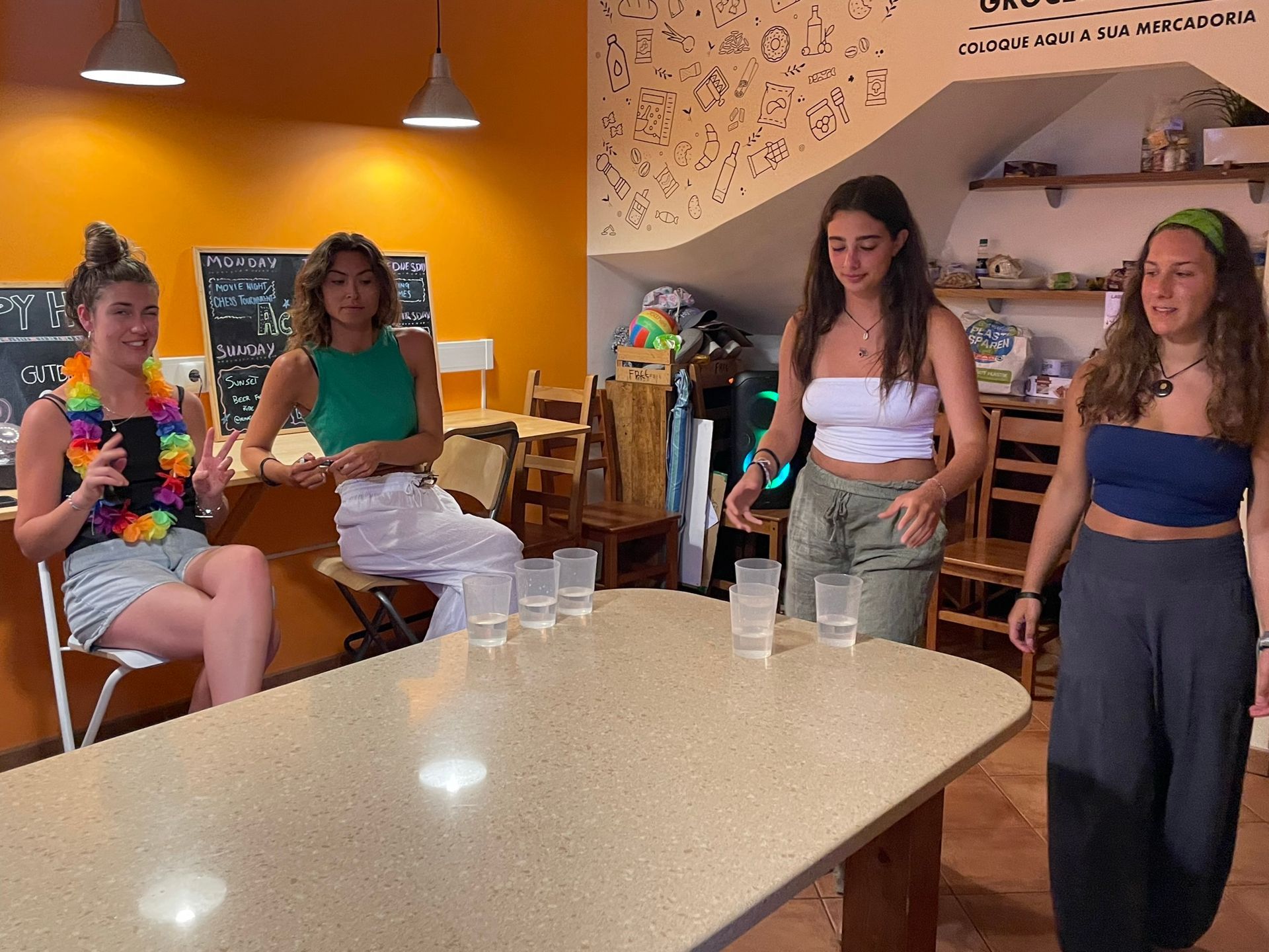 A group of women are standing around a table with glasses on it.