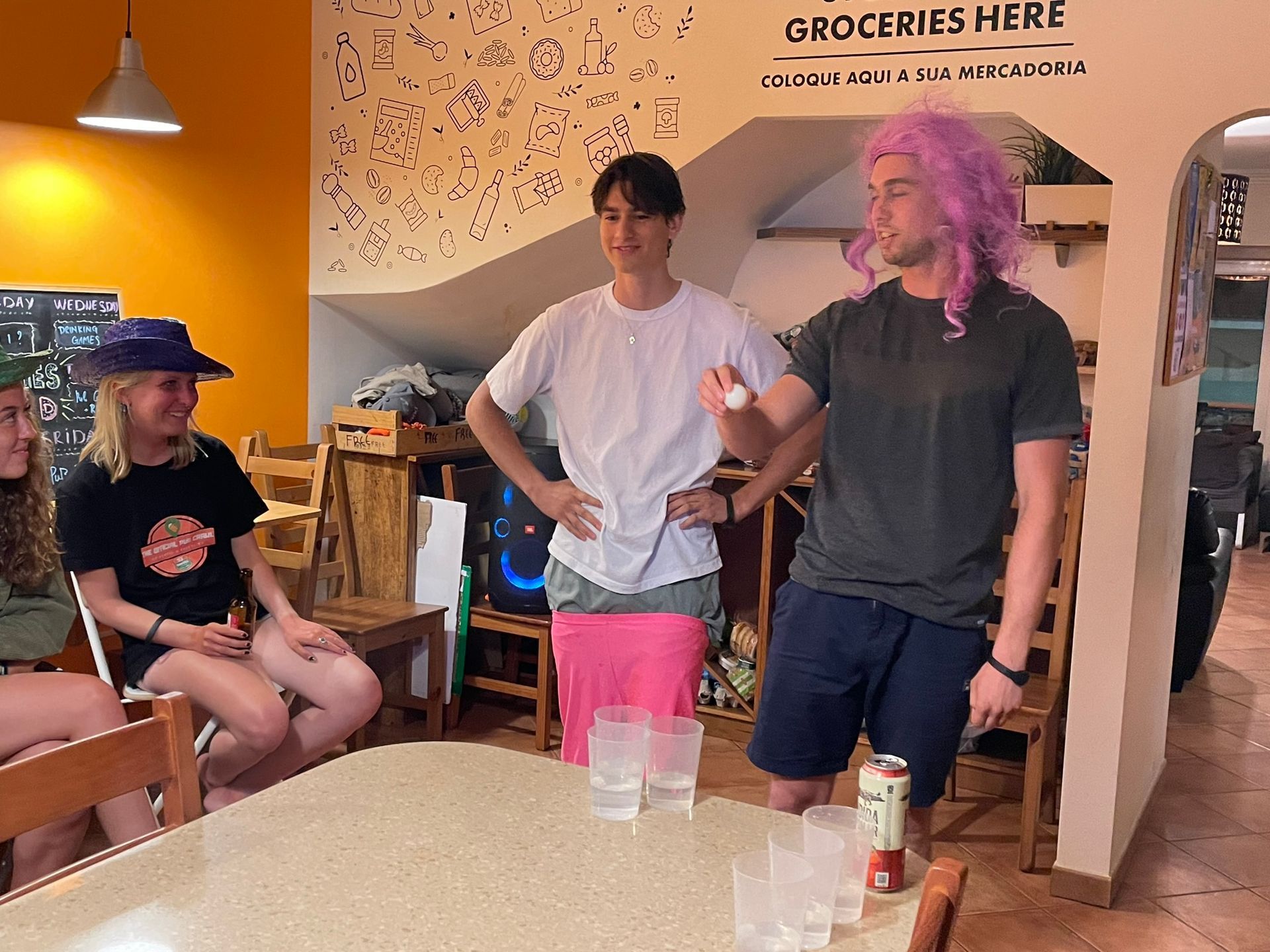 A group of people are standing around a table in front of a sign that says groceries here