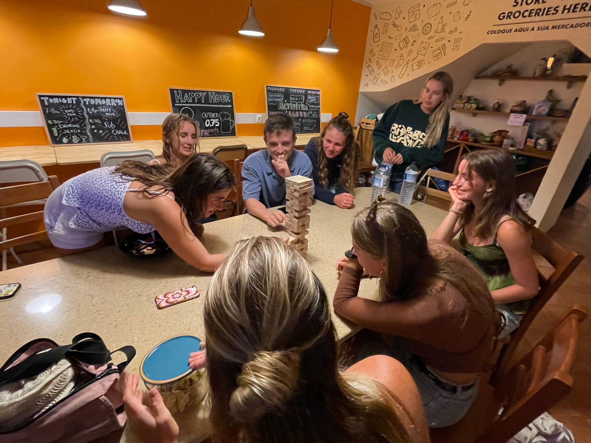 A group of people are sitting around a table playing jenga.