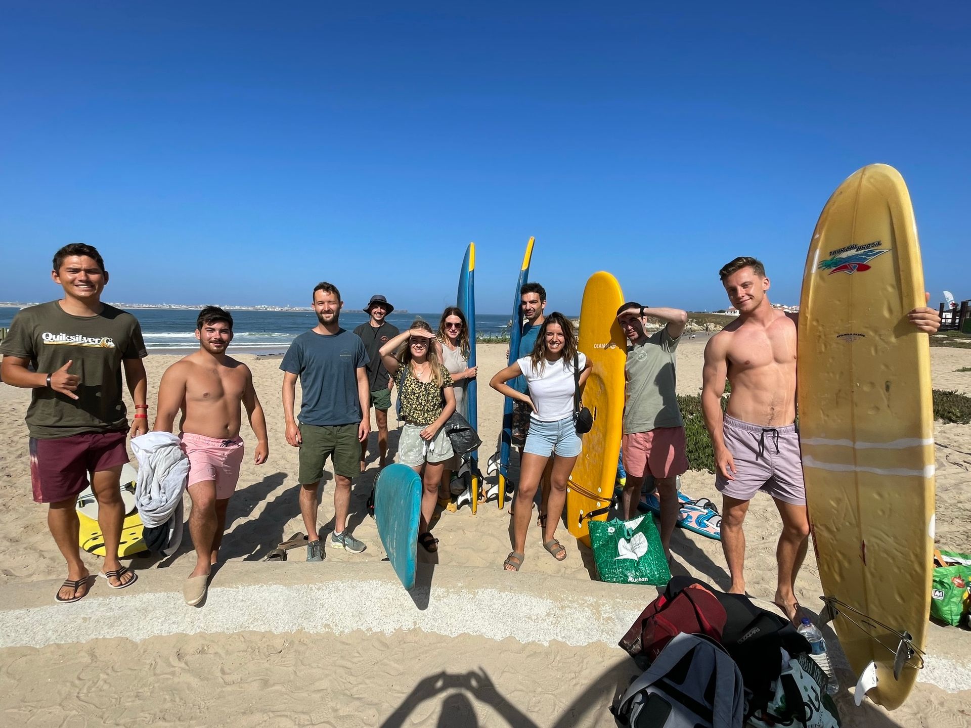 A group of people standing on a beach holding surfboards.