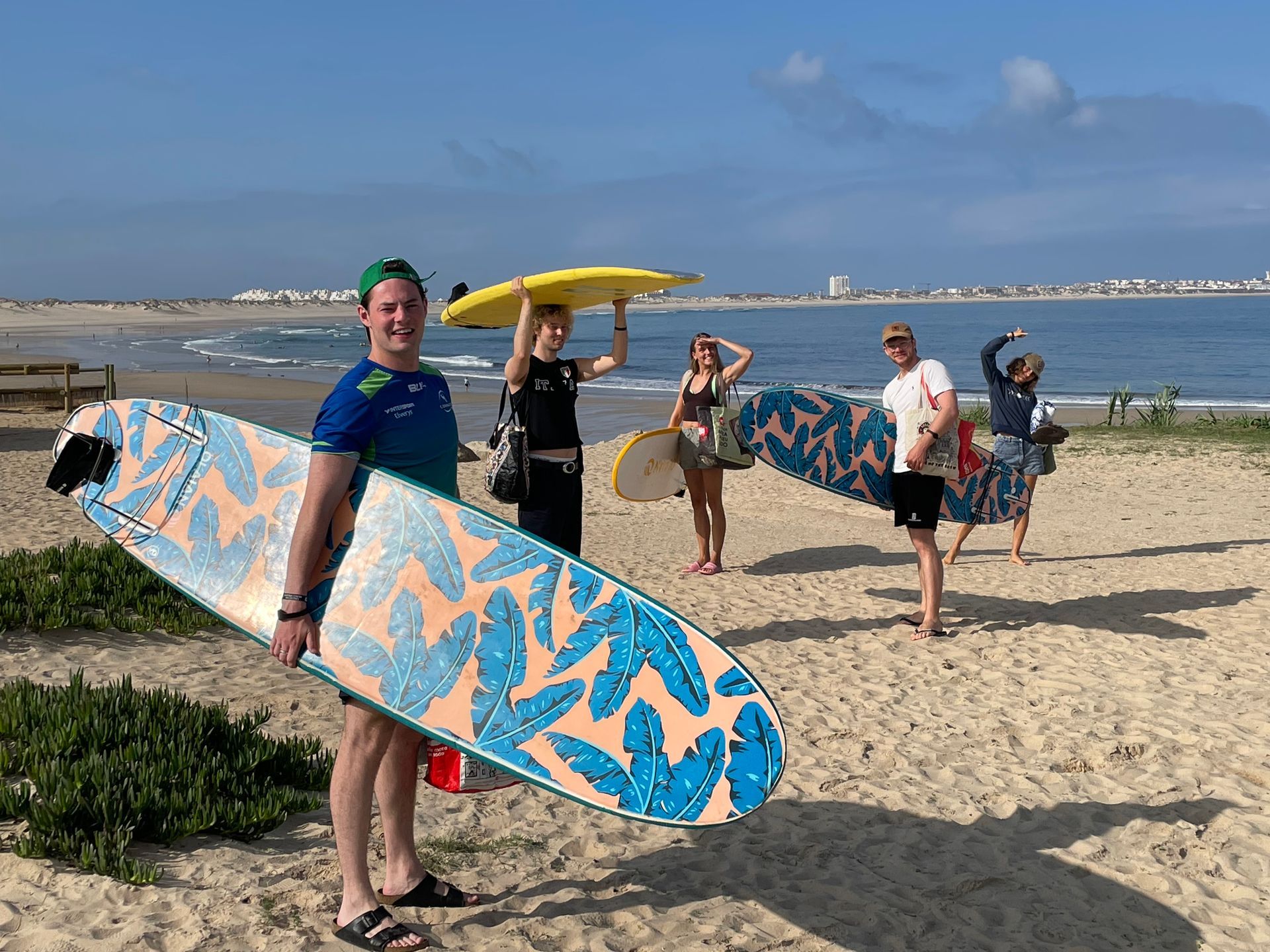 A group of people are standing on a beach holding surfboards.
