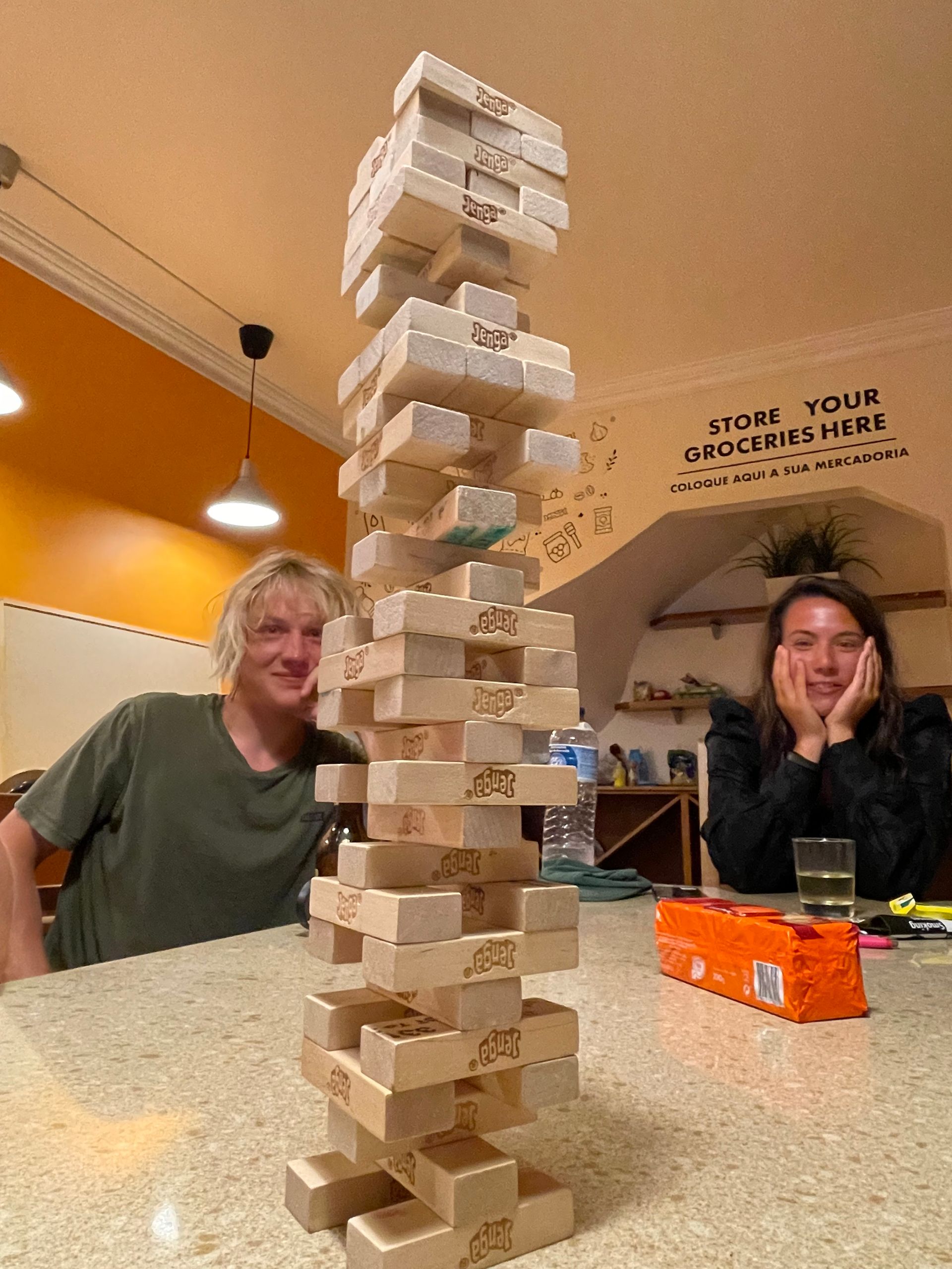 A man and a woman are sitting at a table playing jenga.