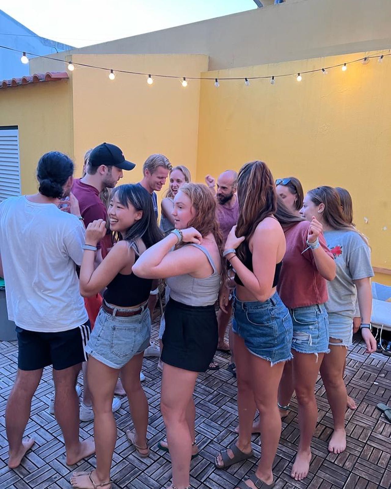 A group of people are dancing in a circle on a patio.