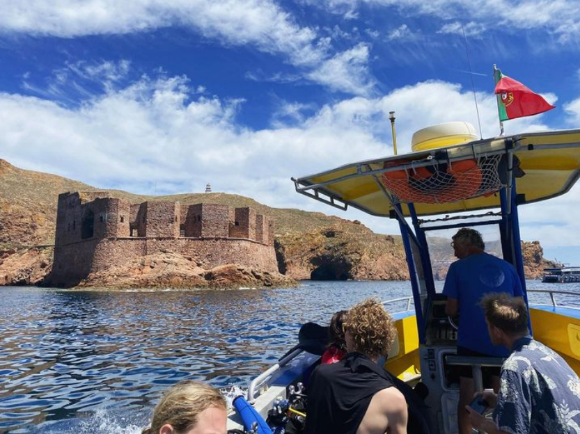 A group of people are on a boat in the water with a castle in the background.