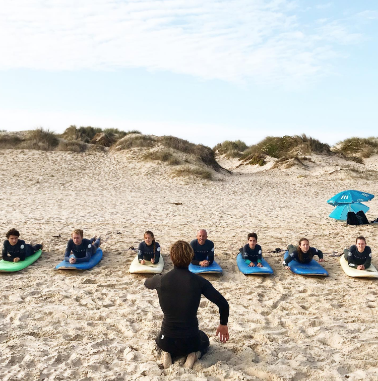 A group of people are sitting on surfboards on the beach